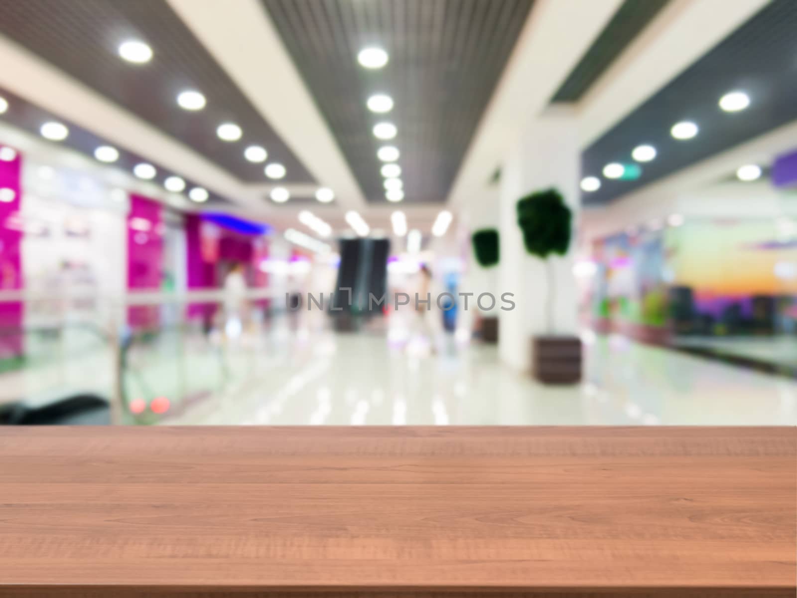 Wooden board empty table in front of blurred background. Perspective dark wood table over blur in shopping mall hall. Mock up for display or montage your product.