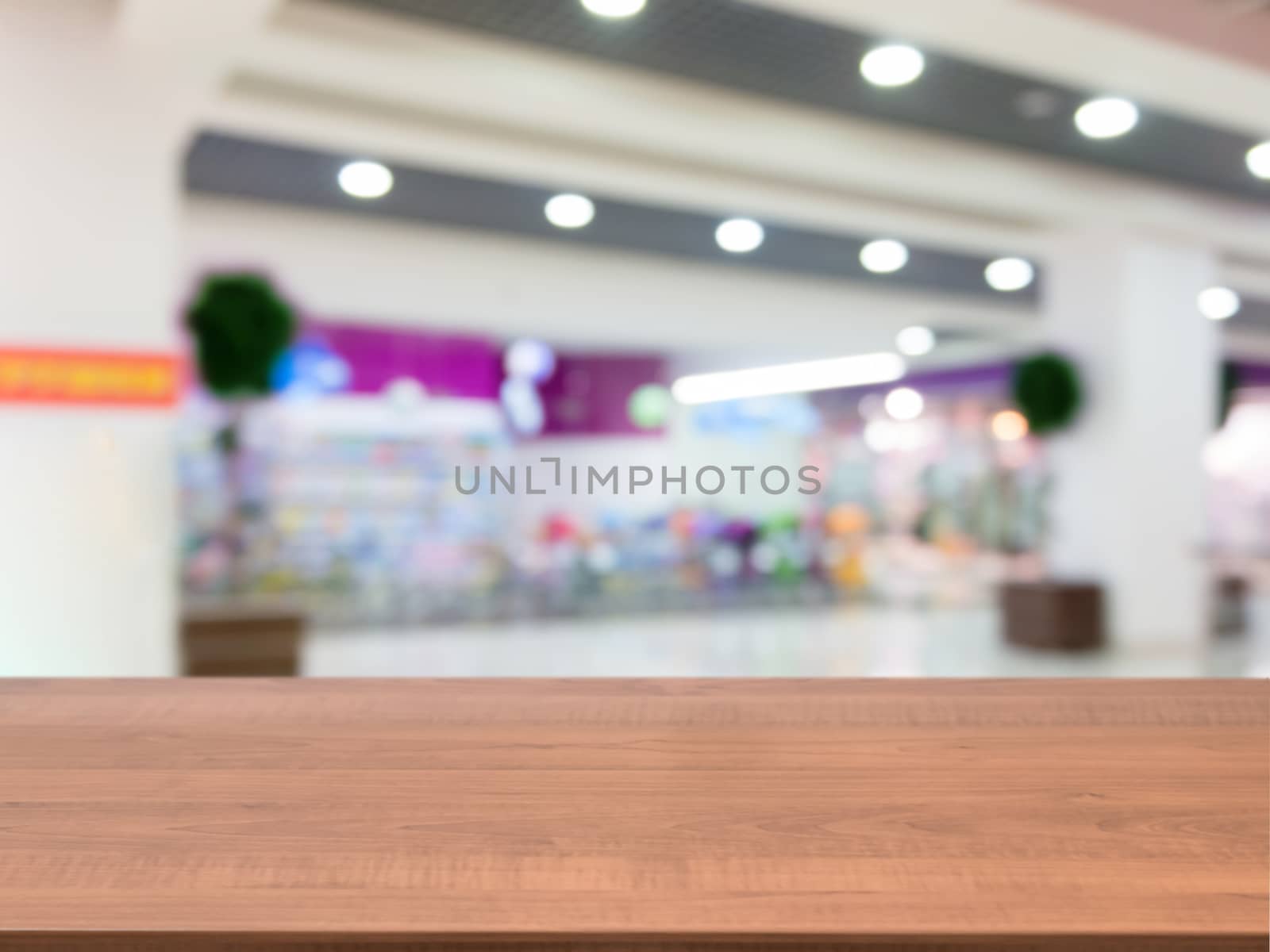 Wooden board empty table in front of blurred background. Perspective dark wood table over blur in shopping mall hall. Mock up for display or montage your product.