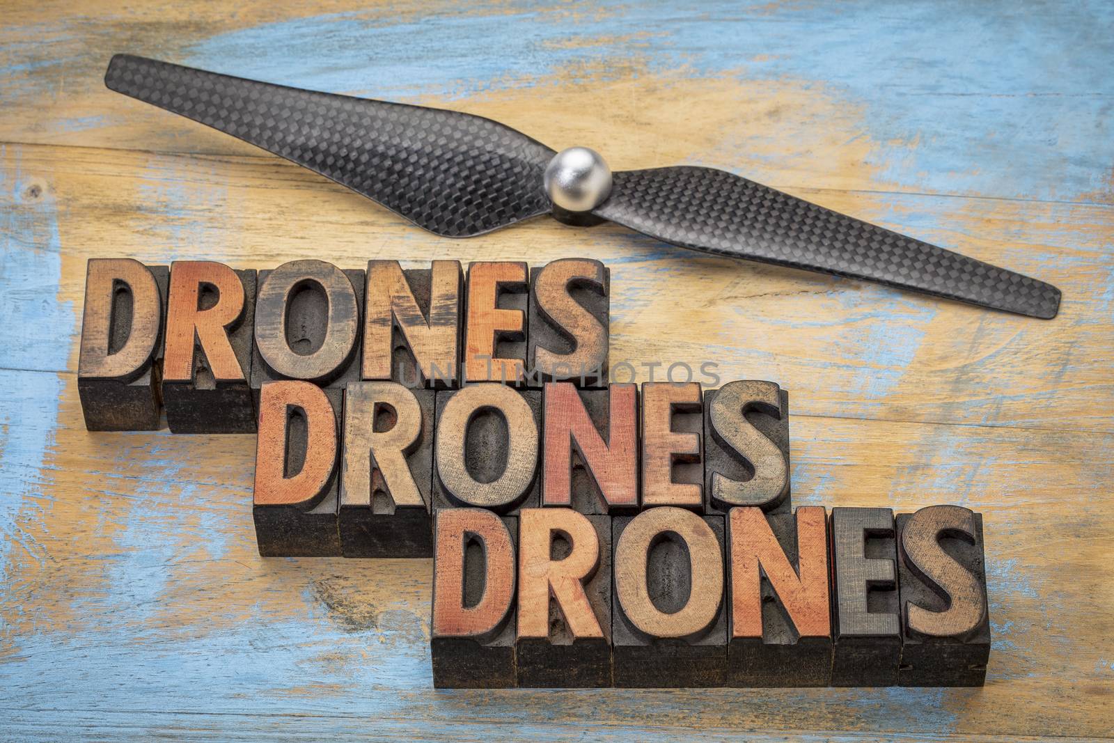 drones word abstract in vintage letterpress  wood type with a drone propeller - new aircraft technology concept