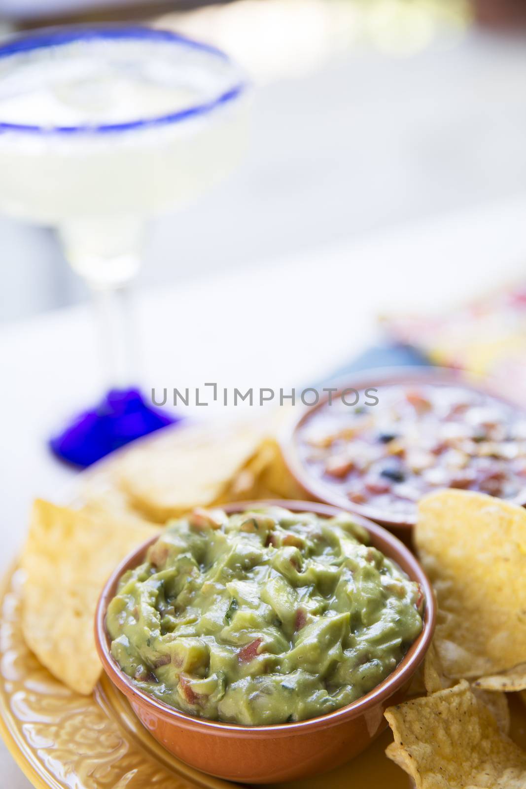 Guacamole and chips with margarita in the background.