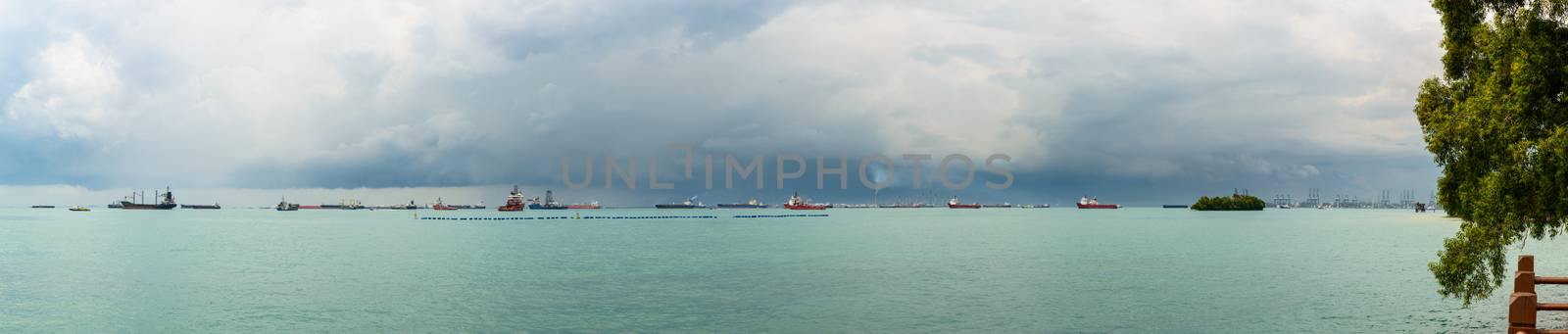 Panoramic view of the Singapore Strait from Sentosa Island. Ships, industrial landscape and stormy weather.