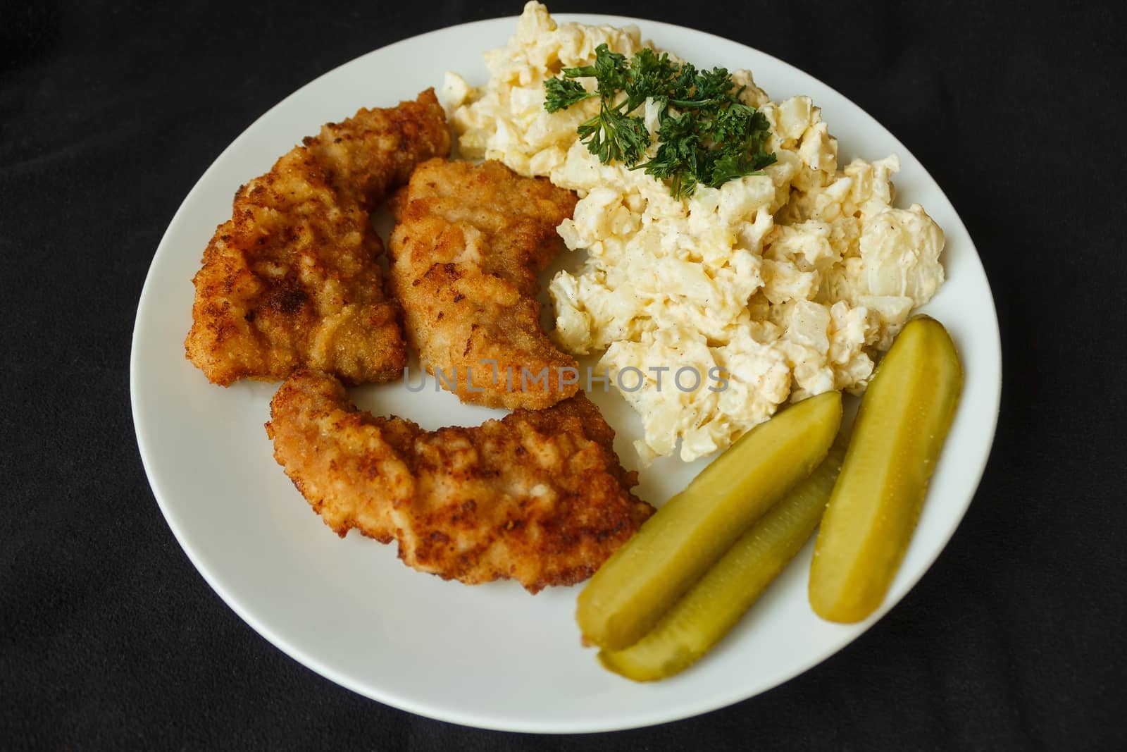 picture taken on Dec. 26, 2015 in Jablonec nad Nisou, Czech Republic schnitzel  and egg salad cucumber parsley white plate on a dark background