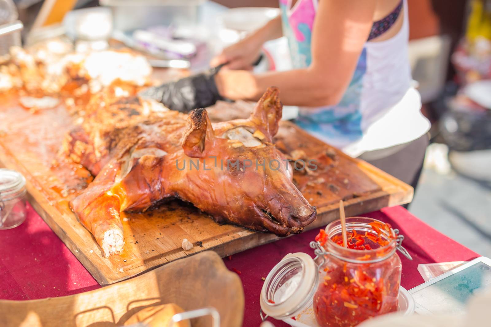 Roasted suckling pig being sliced and served on urban street food stall. Urban international kitchen event in Ljubljana, Slovenia, in summertime.