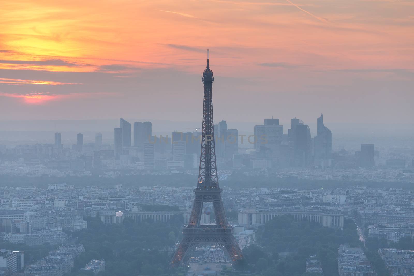 Aerial view of Paris with Eiffel tower and major business district of La Defence in background at sunset.