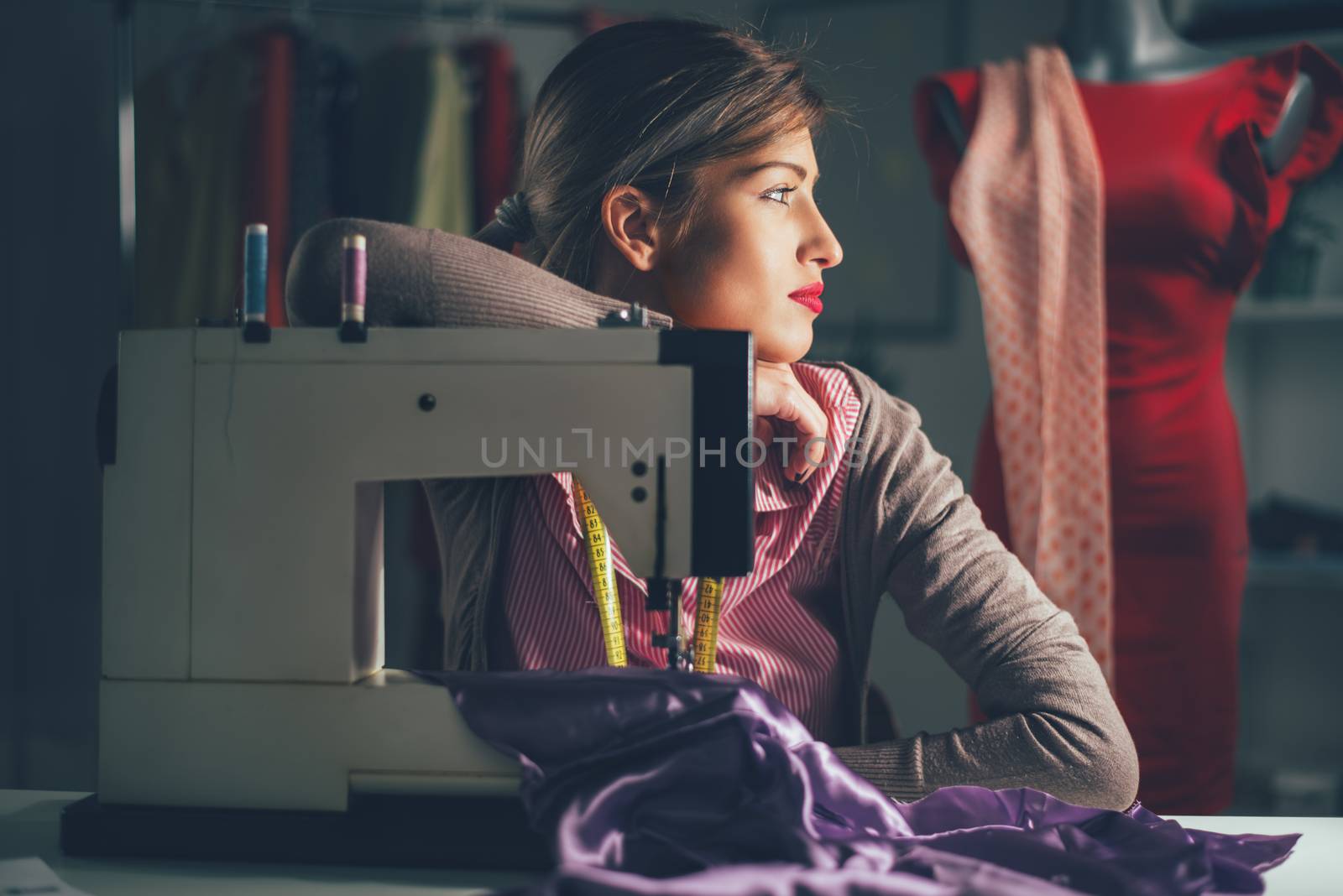 Beautiful tired woman sits in front of the sewing machine and thinking. Vintage concept.