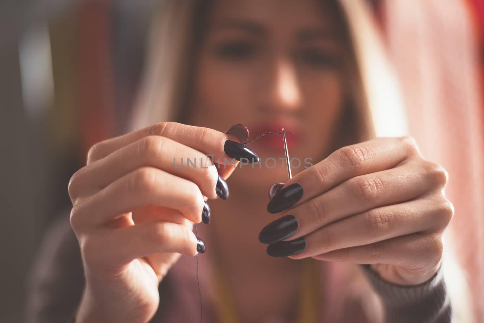 Close-up of female hands passing thread through the needle. Vintage concept.