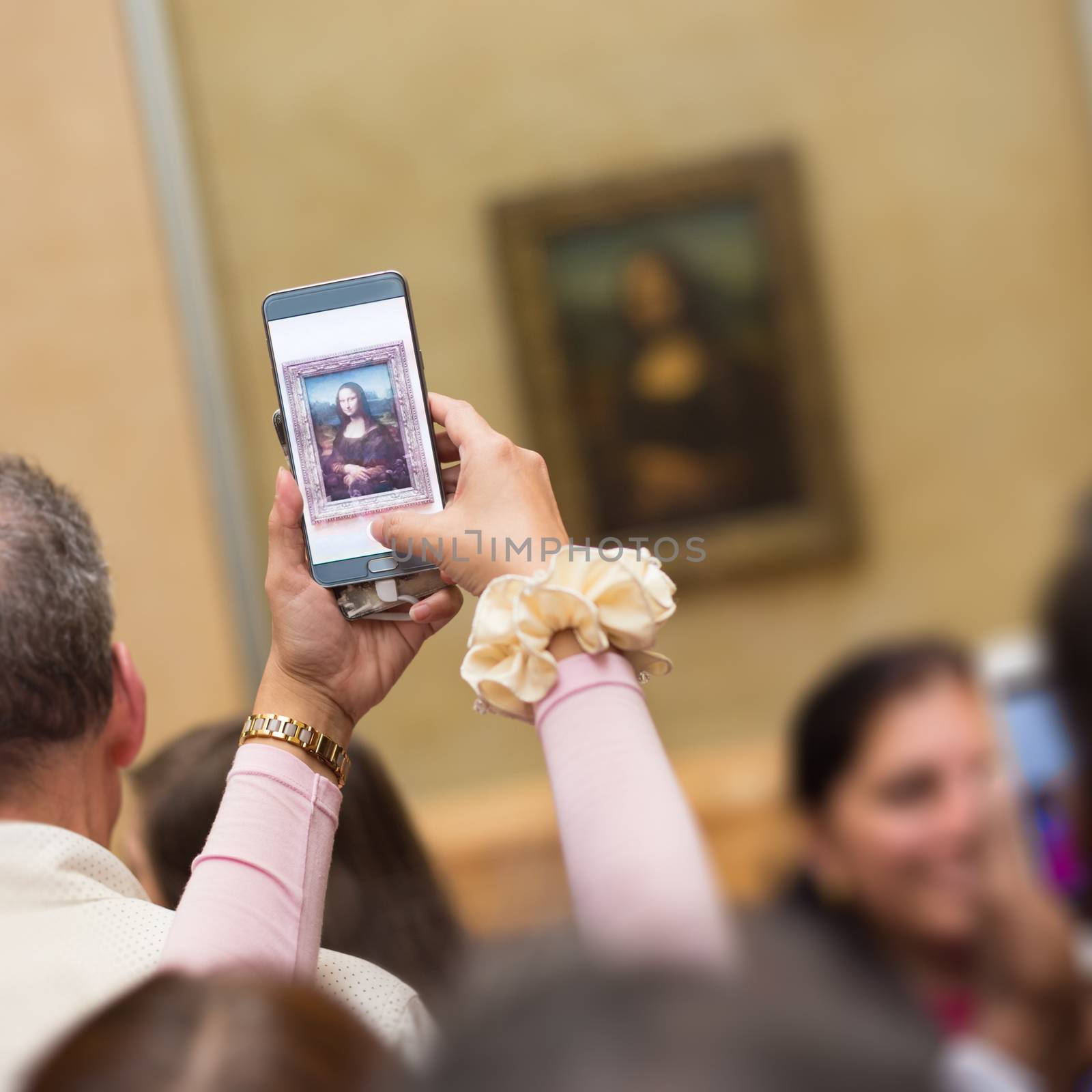 Crowd of visitors takes photos of Leonardo DaVinci's Mona Lisa, one of world's most famous work of art, at Louvre Museum in Paris, France.