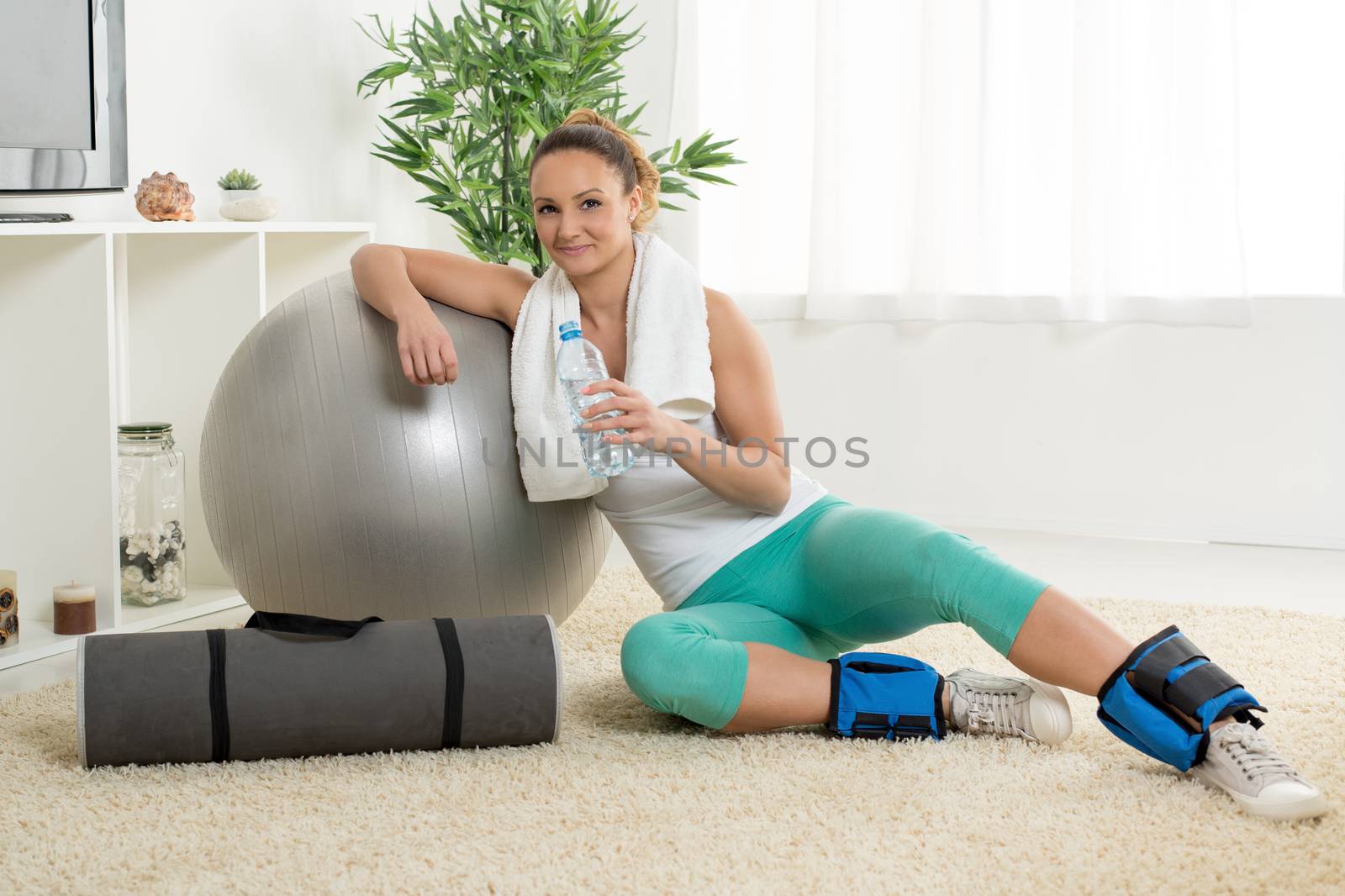Cute young woman resting at home after a hard workout. Looking at camera.