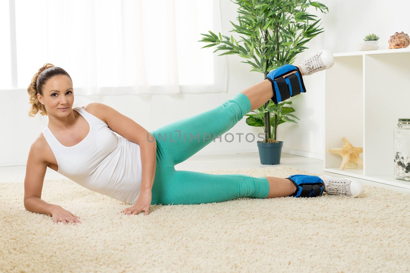 Beautiful young woman exercising with dumbbells at home.