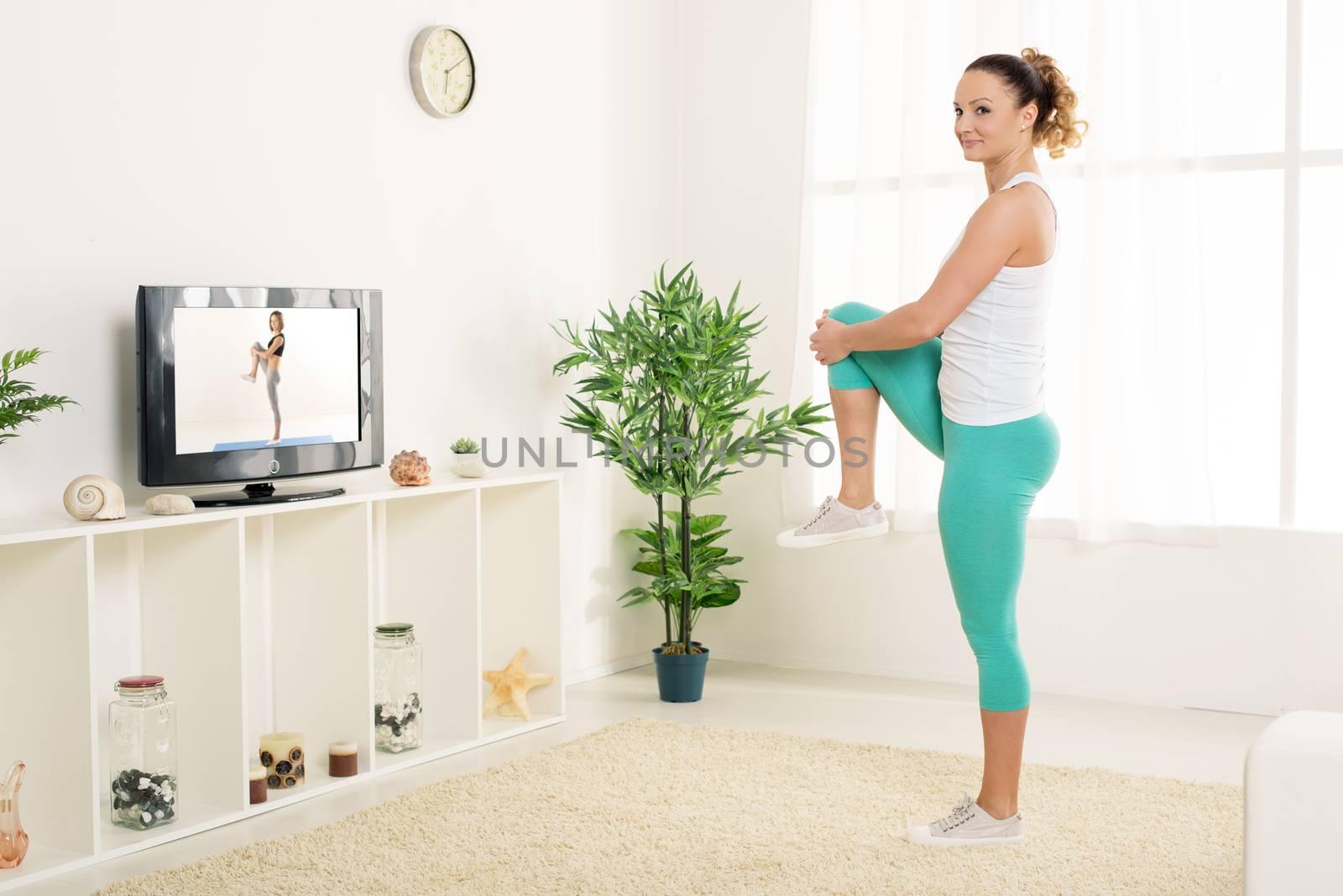 Beautiful young woman stretching out her legs at home in front of the tv