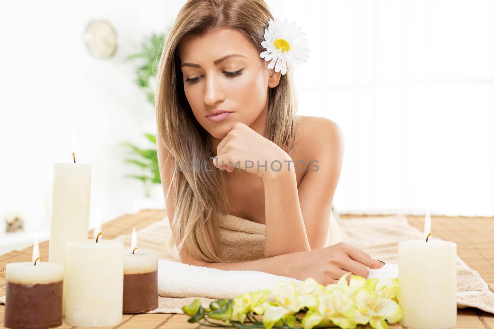 Cute young woman enjoying during a skincare treatment at a spa. She is thinking and her head is resting on her hand. 