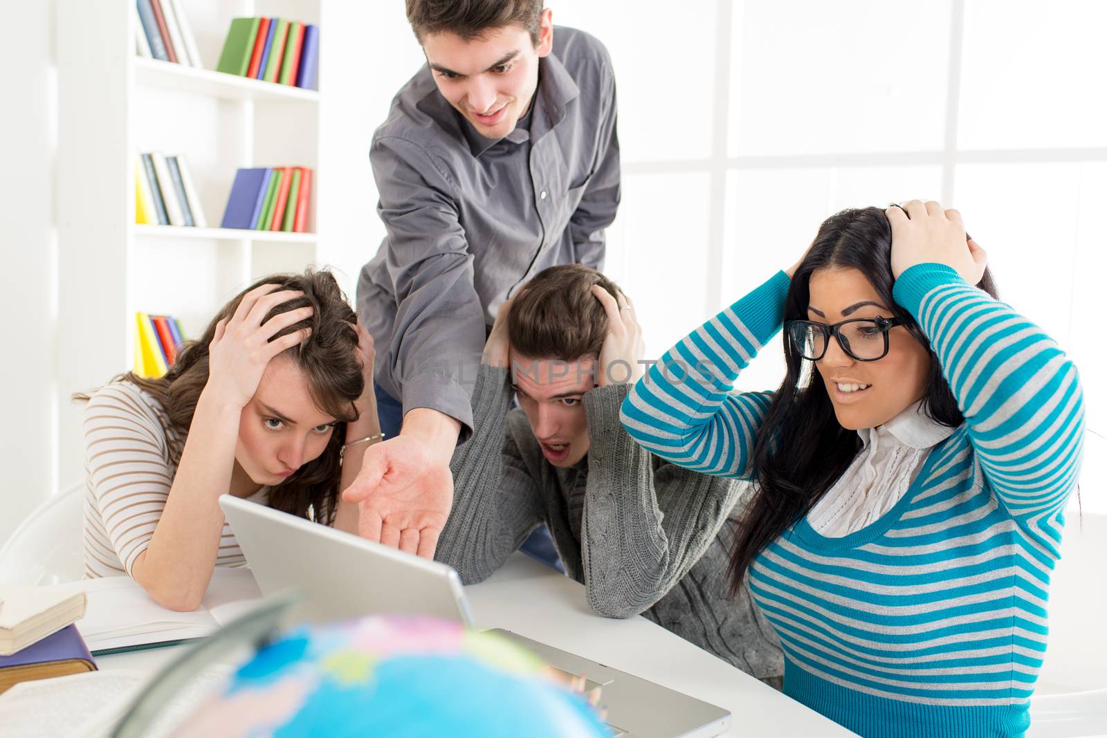 Four woried students of Geography sitting with laptop and learning.