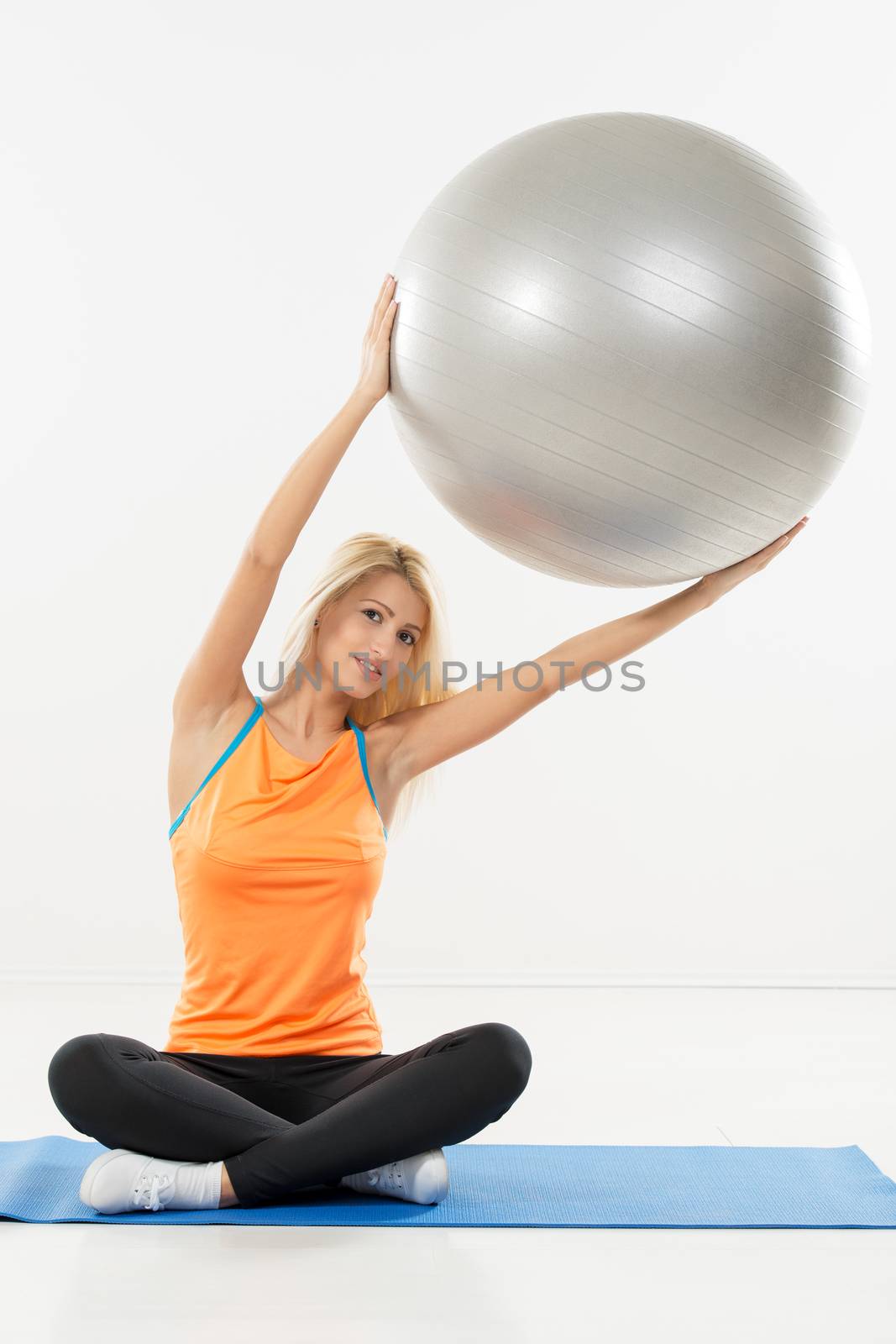 Cute young woman exercising with fitness ball. White background.