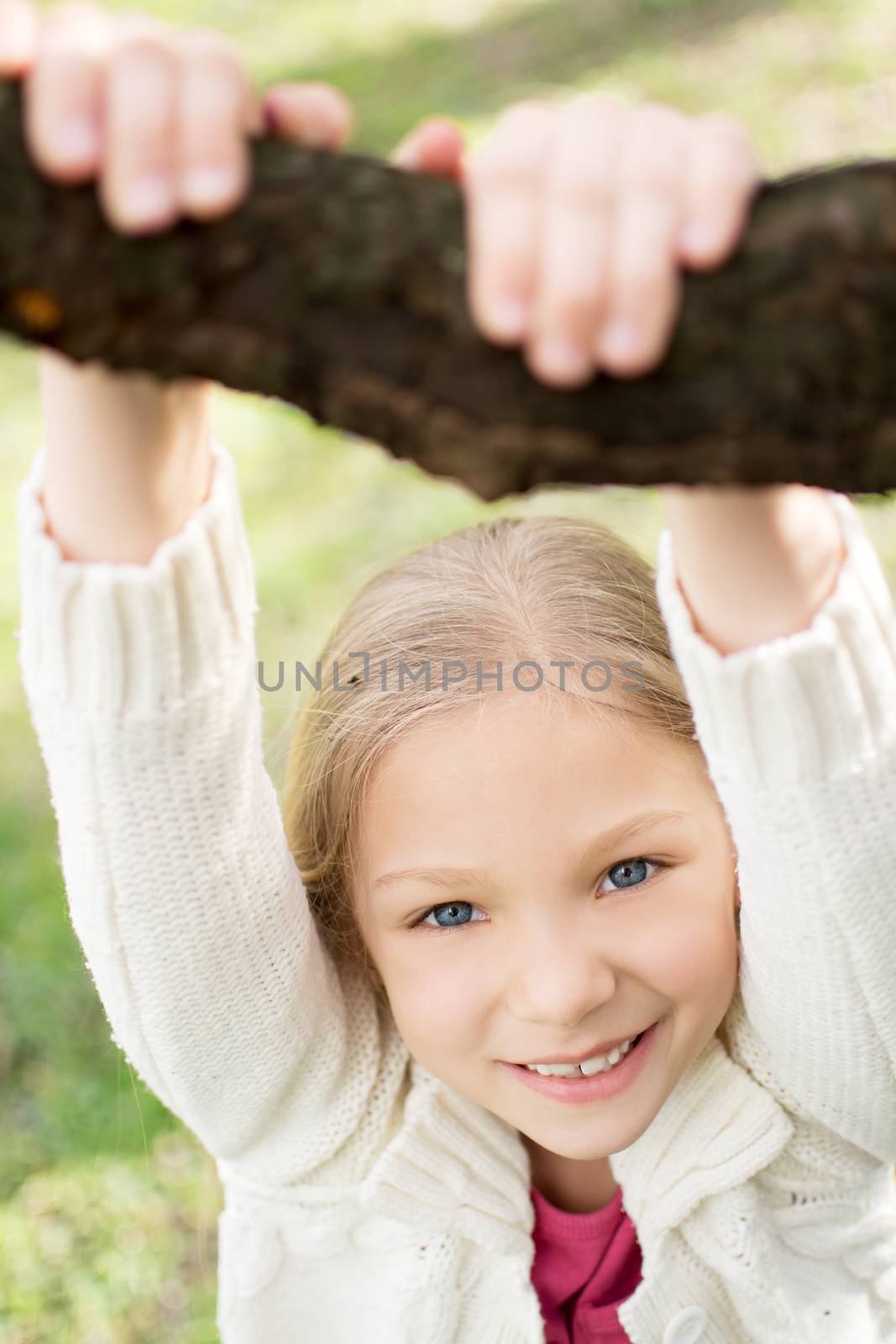Beautiful funy little girl in the park in spring. Looking at camera.