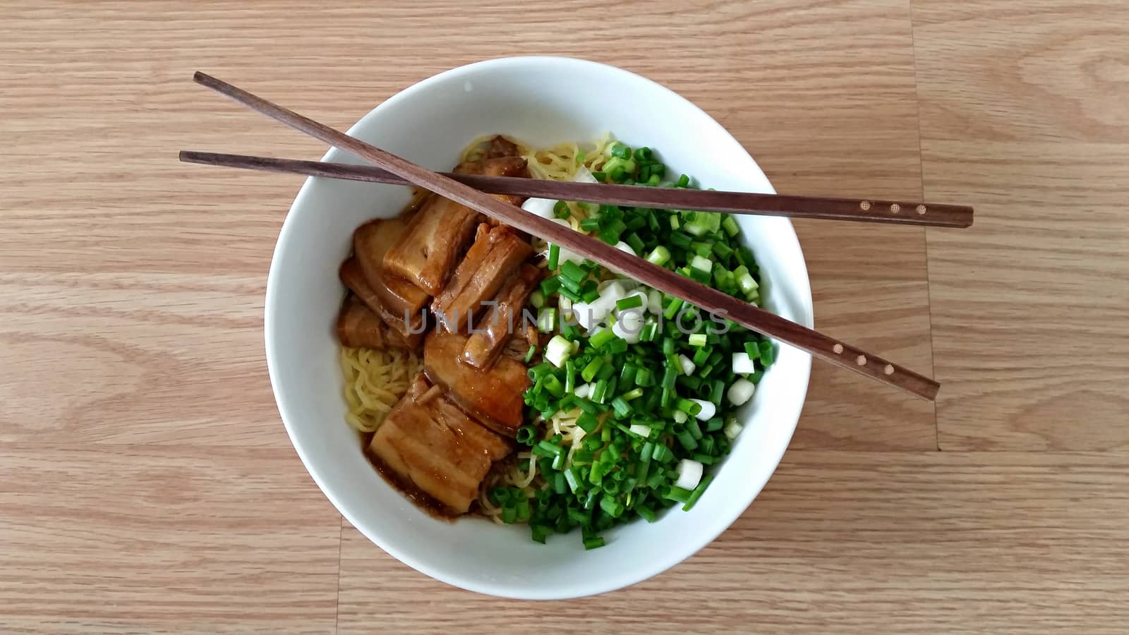 Egg noodle with steam pork belly in a bowl with chopsticks 