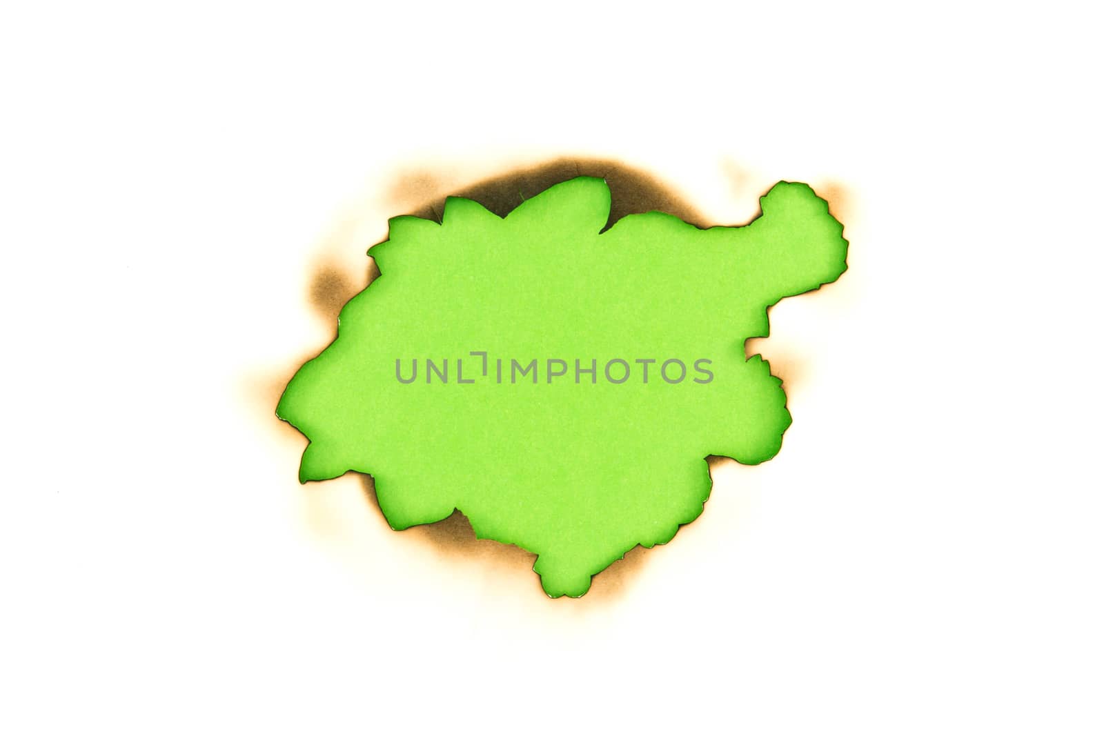 Burnt hole in a paper over green paper background 
