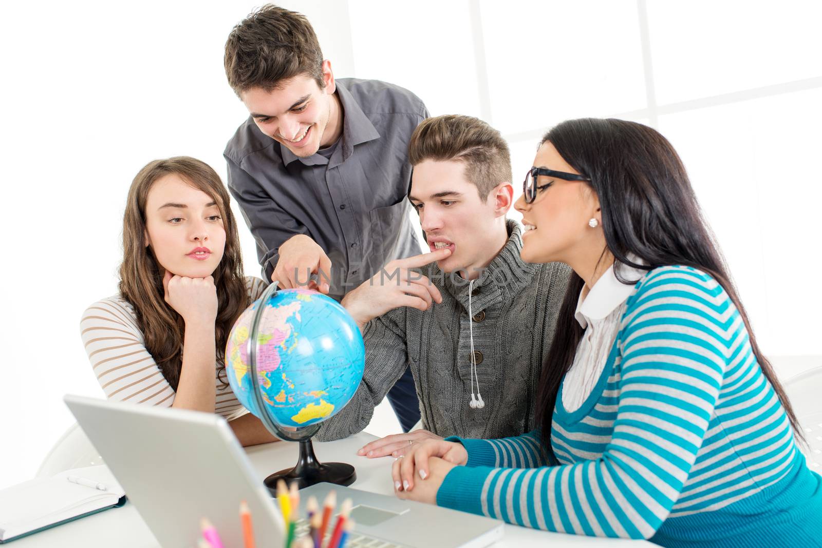 Four beautiful students of Geography learning with globe and laptop.