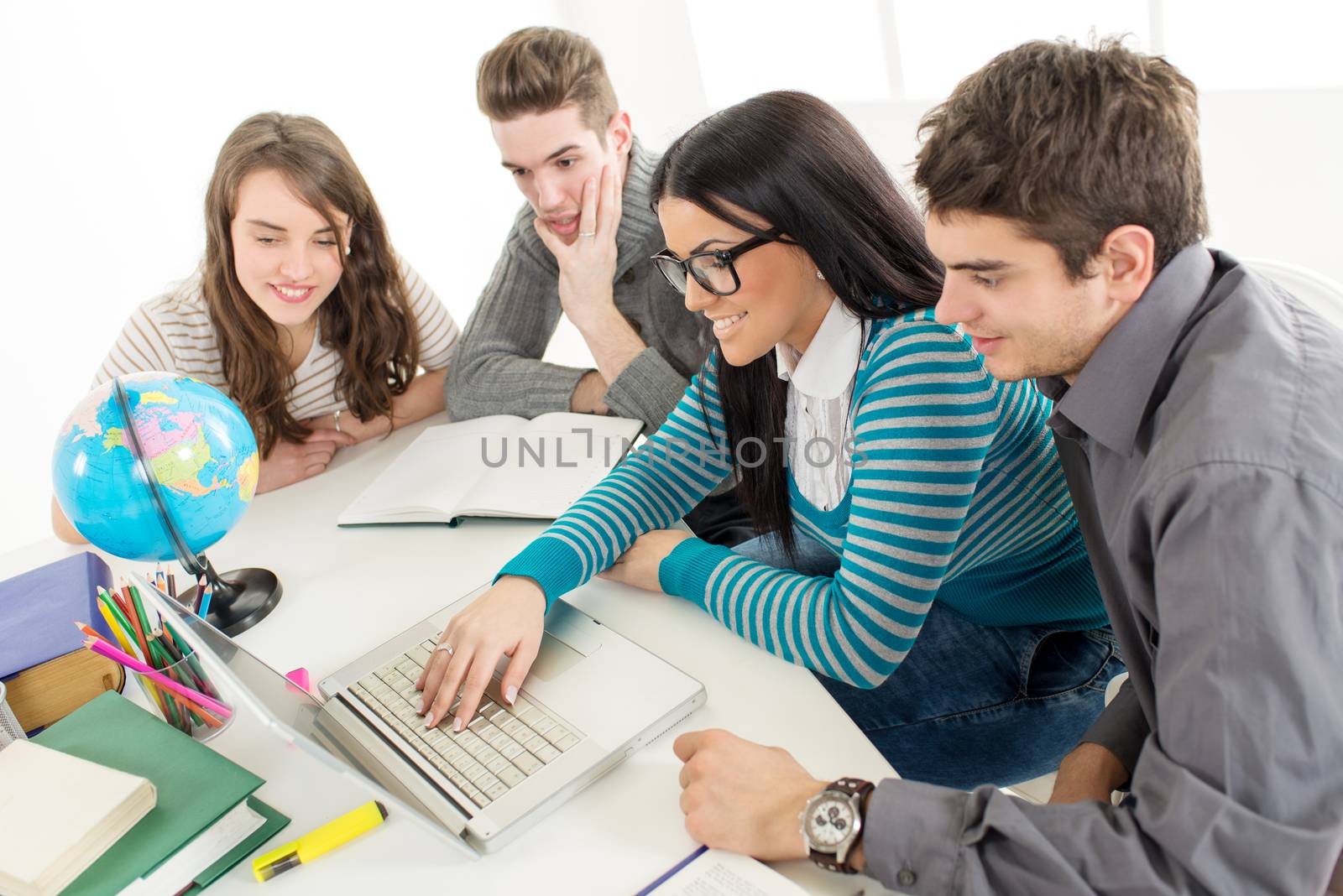 Four beautiful students of Geography learning with globe and laptop.