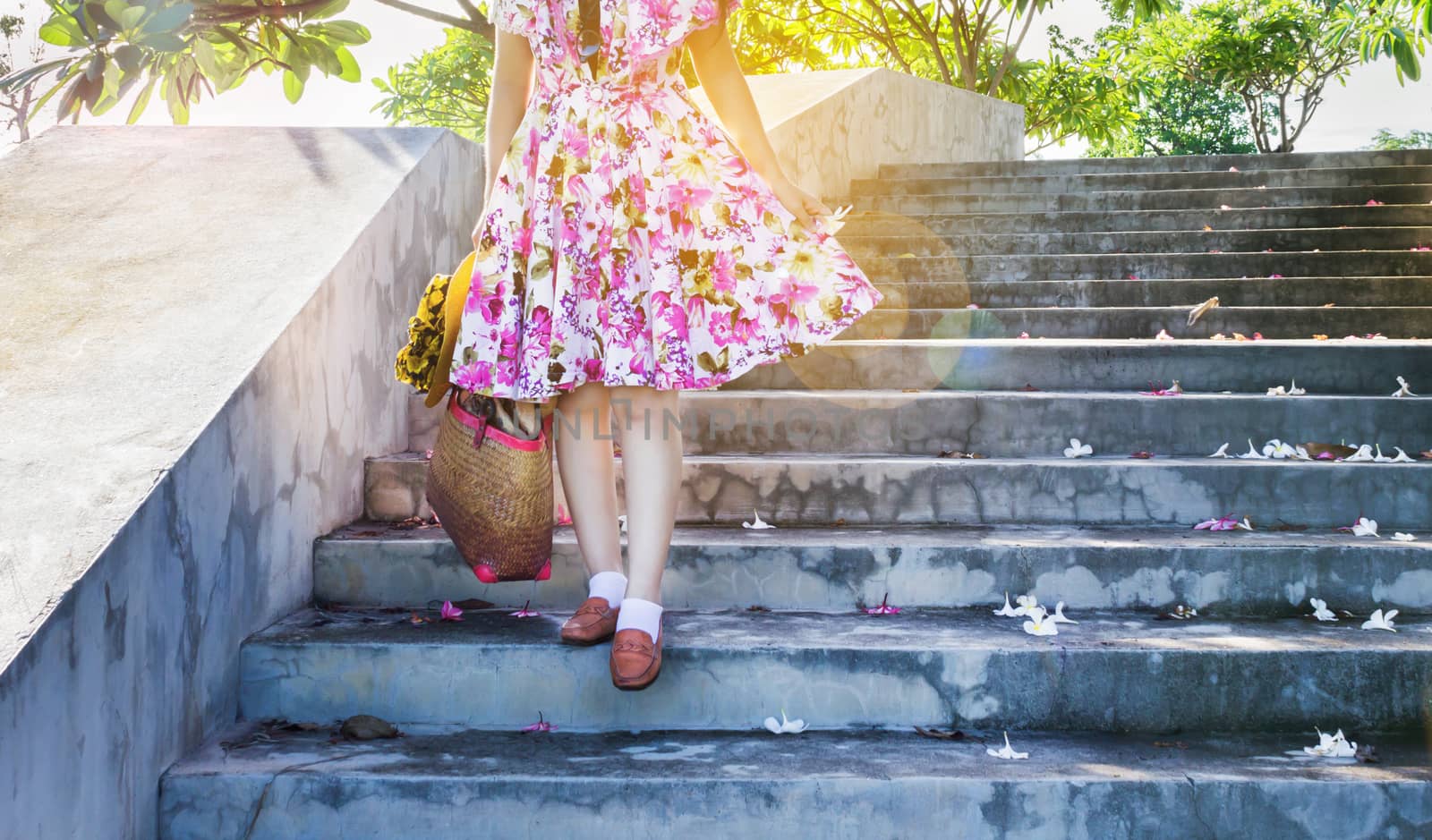 Focused at walking down on concrete stair, girl or women in flowers pattern dress with summer feeling, women go for a walk in spring or summer