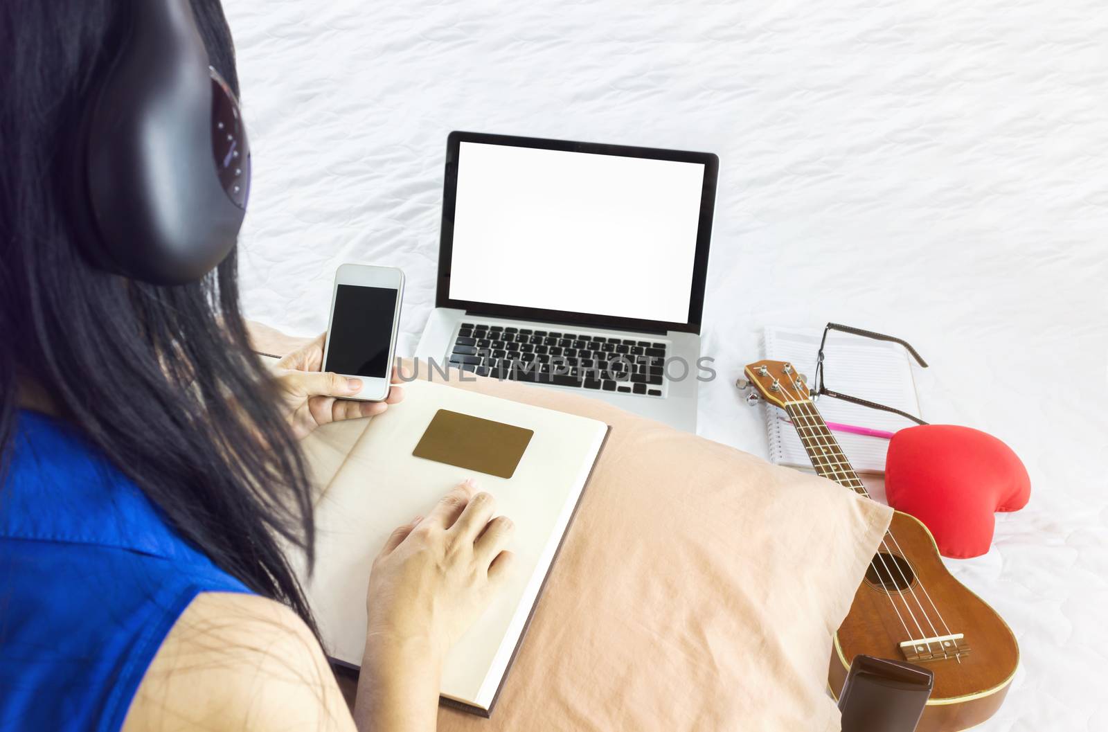 Blank laptop screen with Asian girl sitting on bed surfing inter by KAZITAFAHNIZEER