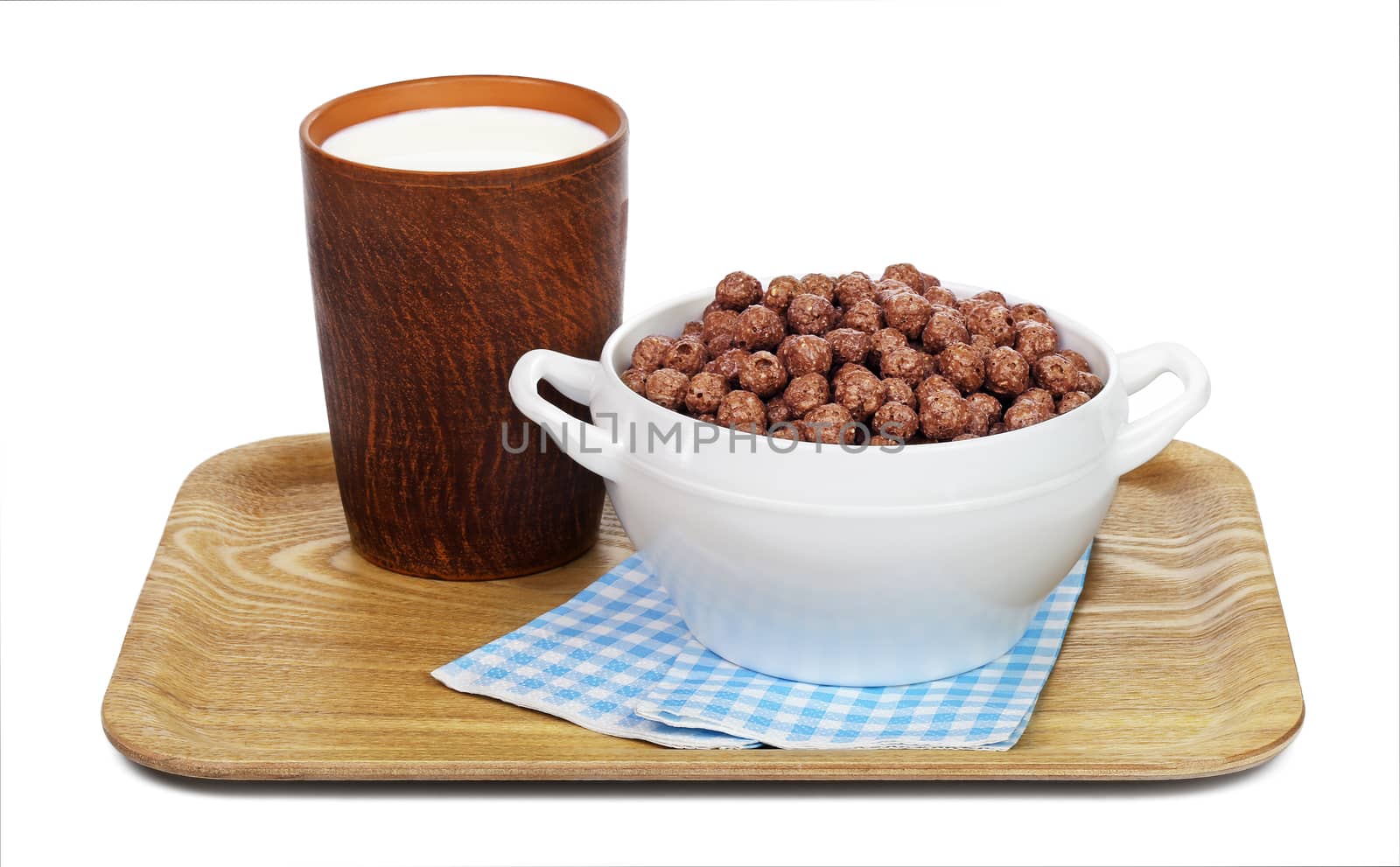 Chocolate cereal balls in a white bowl and a ceramic mug with milk on a wooden tray with paper napkins, isolated on white background.