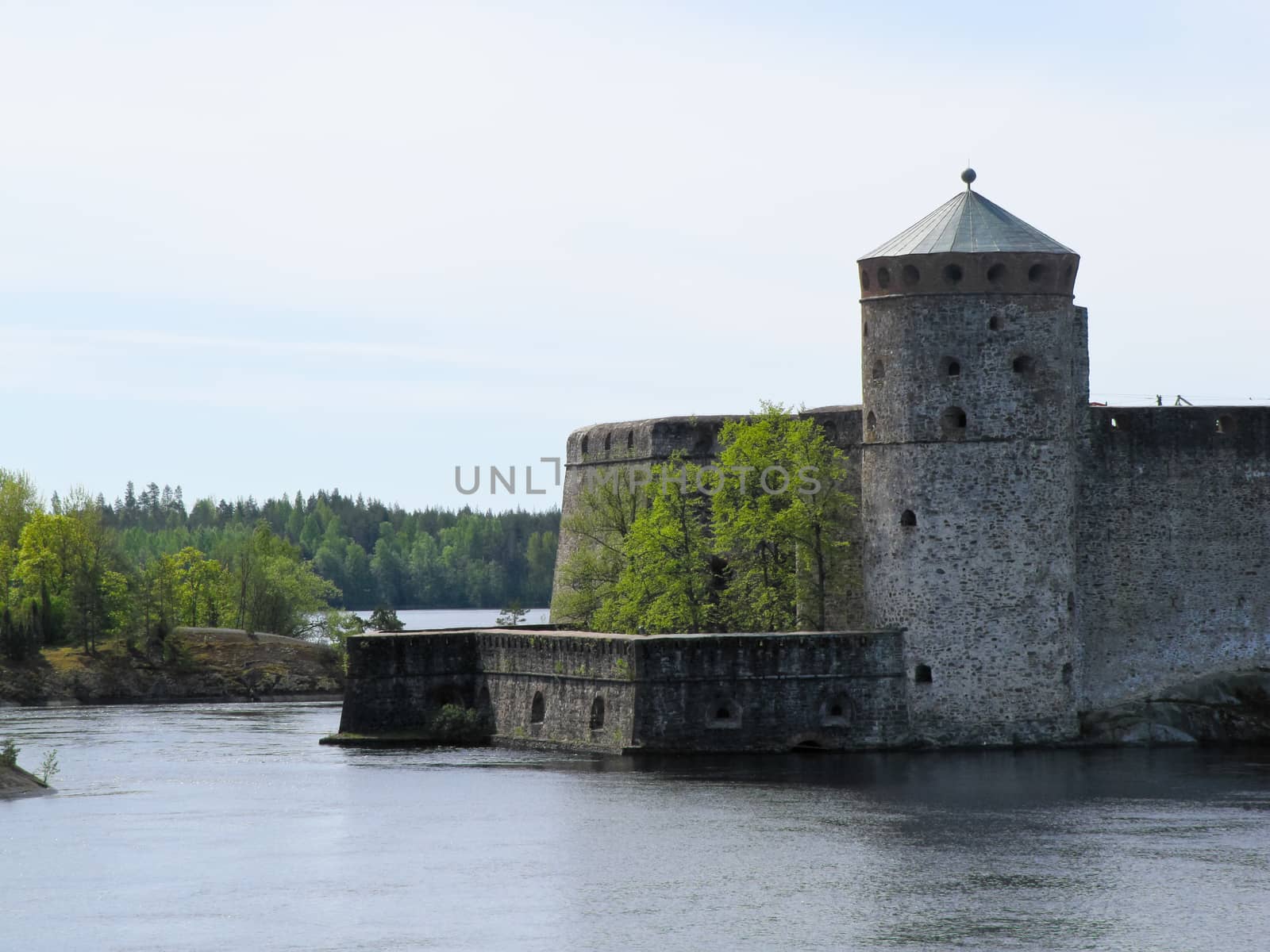 old castle by the river on a background of forest and blue sky