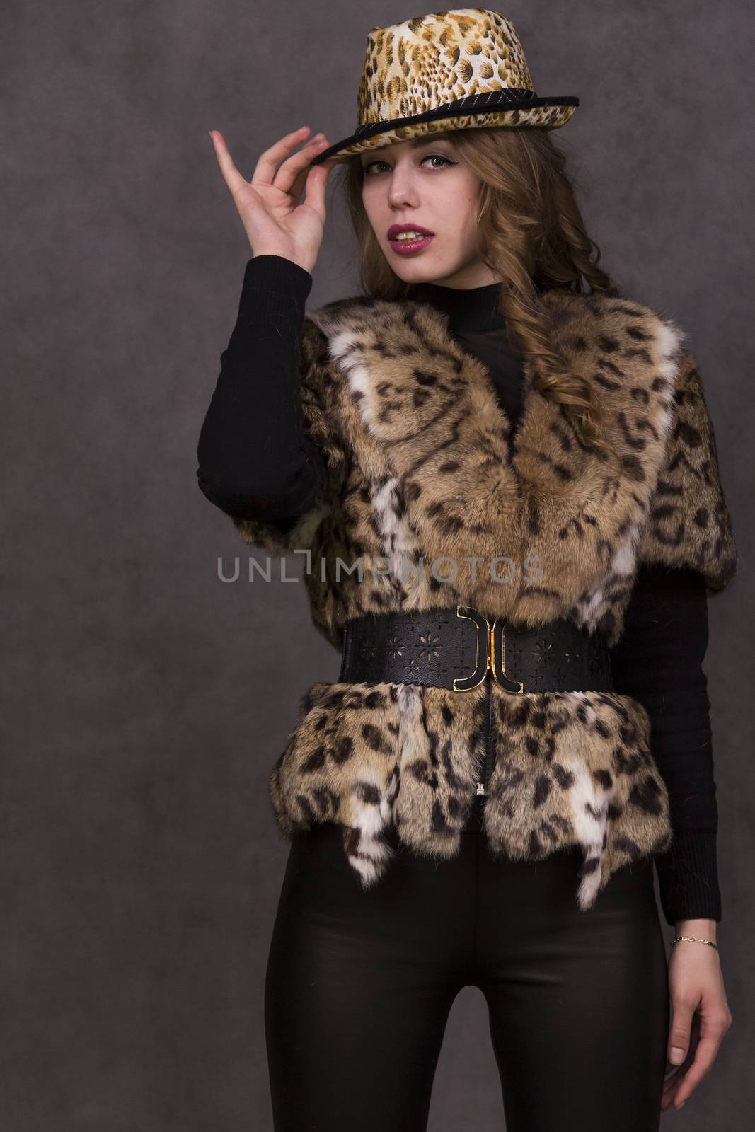 Girl model in fur coat and Leopard Hat posing on grey background in the Studio.