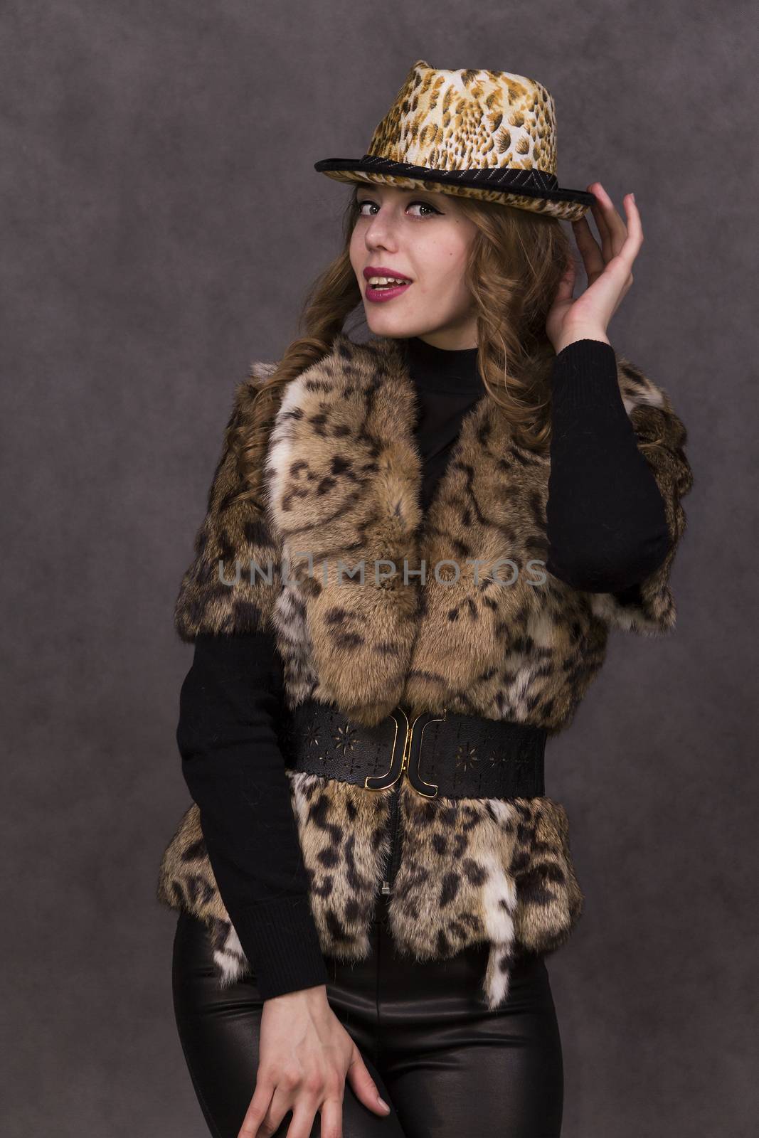 Girl model in fur coat and Leopard Hat posing on grey background in the Studio.