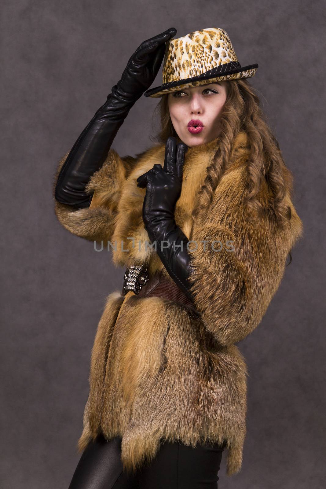 Girl model in fur coat and Leopard Hat posing on grey background in the Studio.