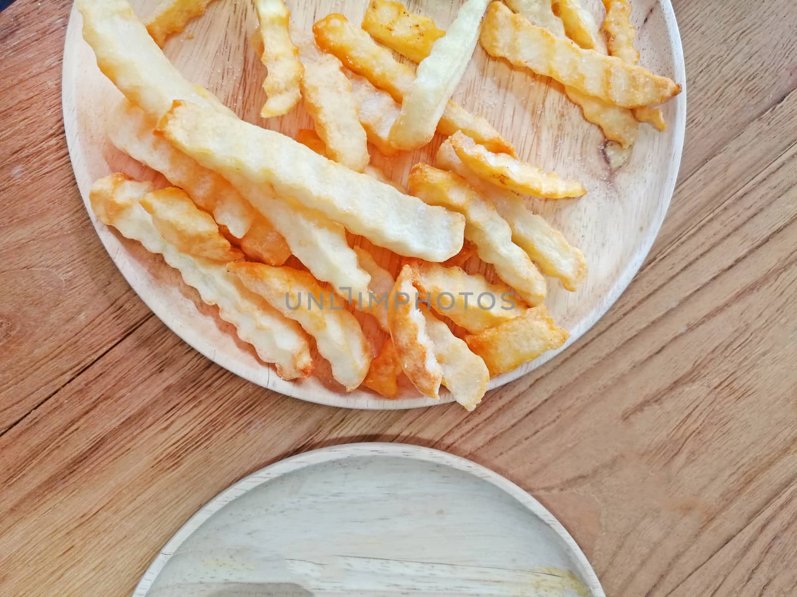 Traditional French fries on wood background.