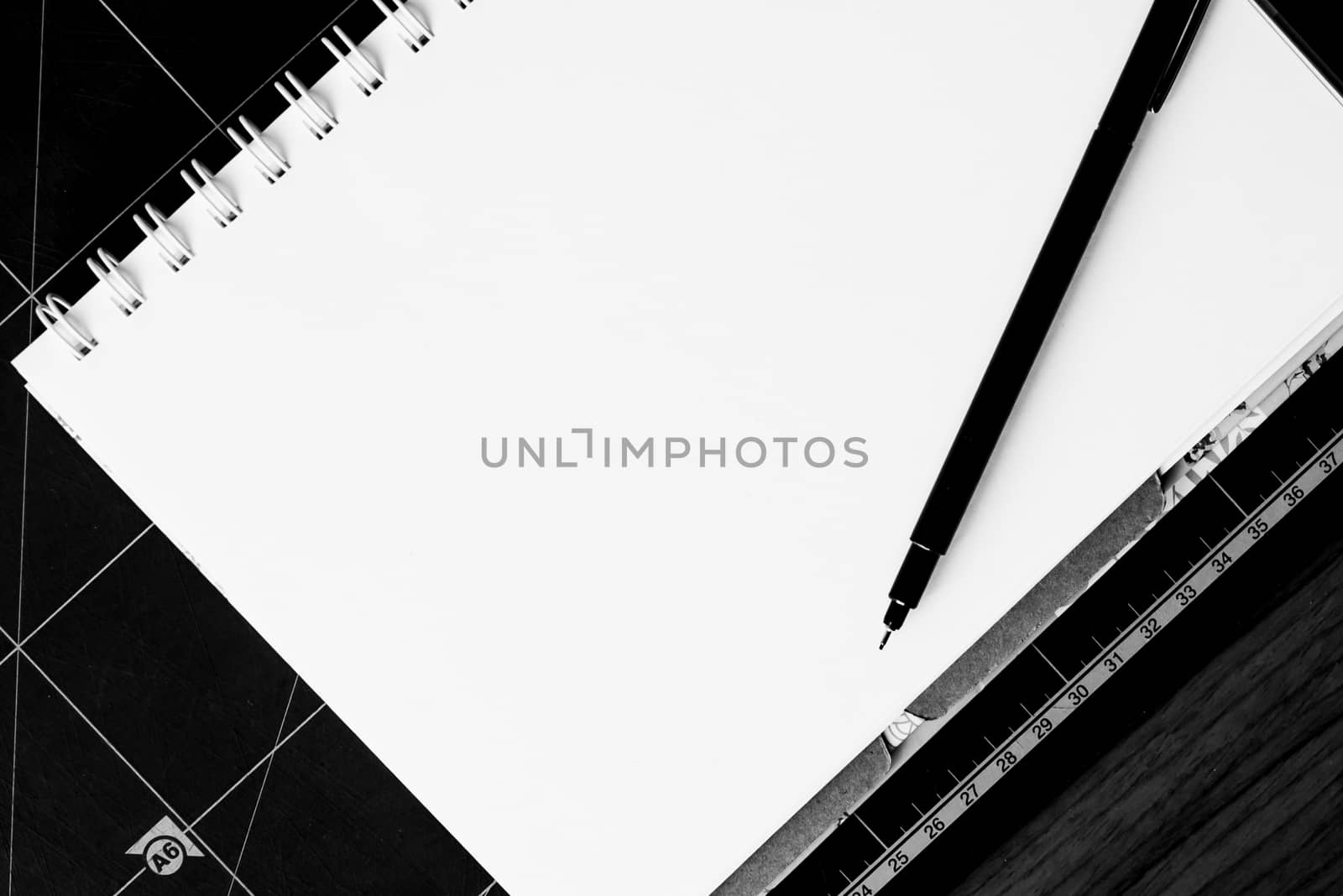 Blank notebook with pen on the table. black and white image. by toodlingstudio