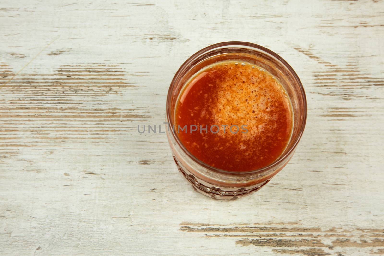 Gass of fresh tomato juice, on a wooden countertop in vintage style. Flat,horizontal view.