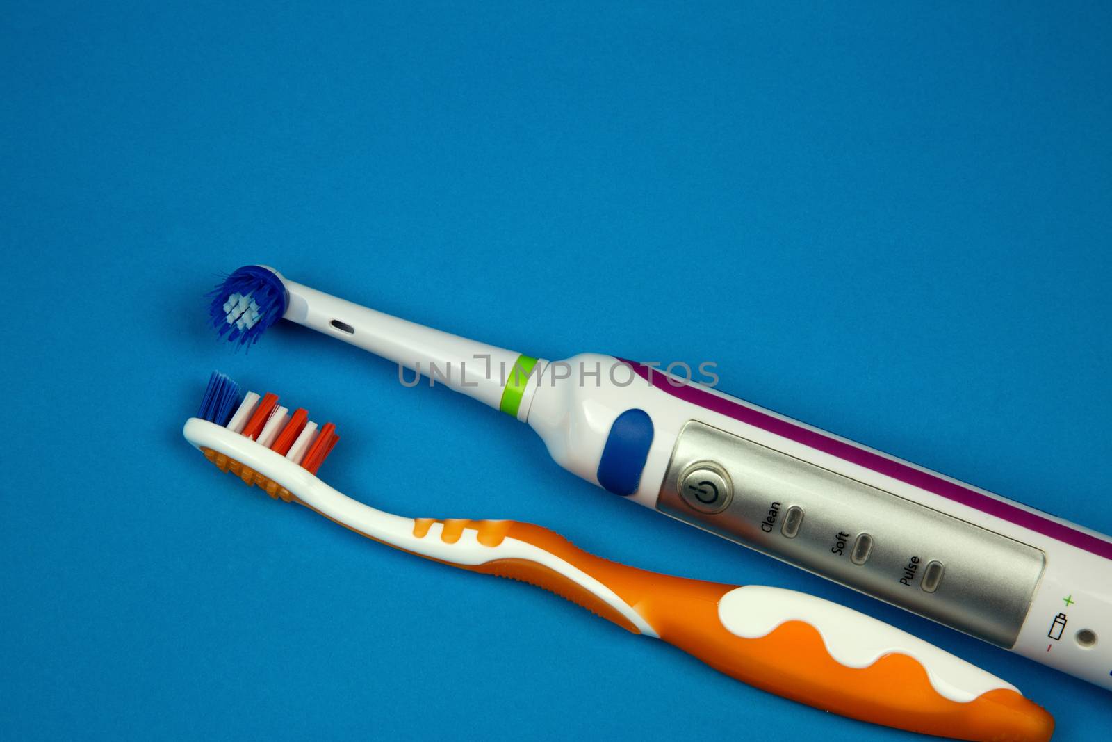 Electric and classical toothbrush on  isolated blue background, flat,horizontal view.
