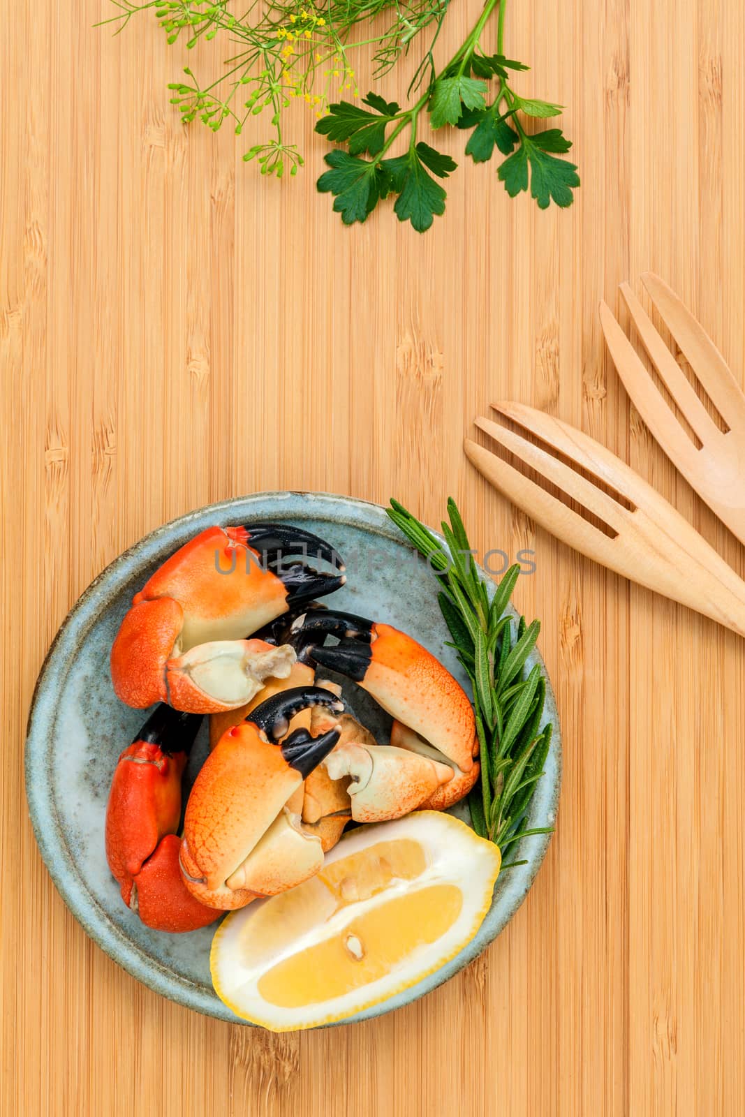 Fresh steamed red crabs leg in bowl . Red crabs leg with ingredients. Steamed red crabs leg with herbs Fennel ,parsley,rosemary,lemon and mint with fork on wooded cutting board.