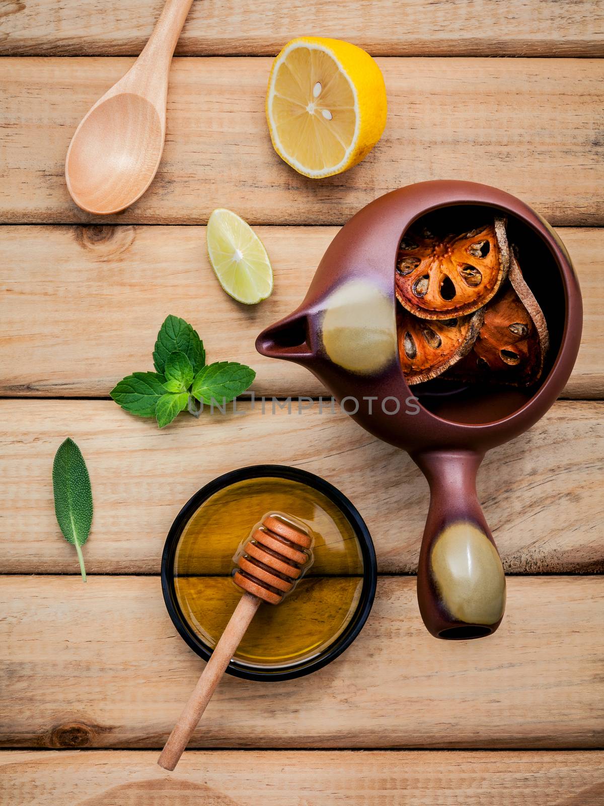 Herbal tea pot with fresh herbs sage ,peppermint ,dried indian bael, honey, lime and lemon on rustic wooden background.