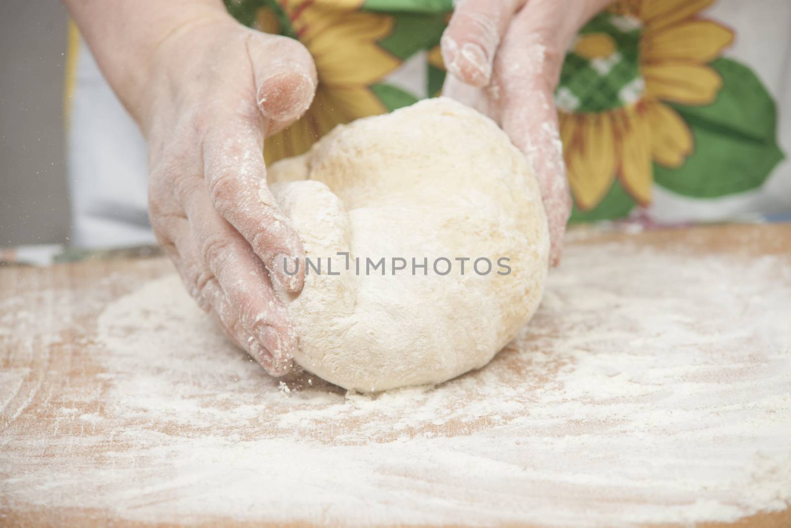 Women's hands preparing fresh yeast dough on wooden table