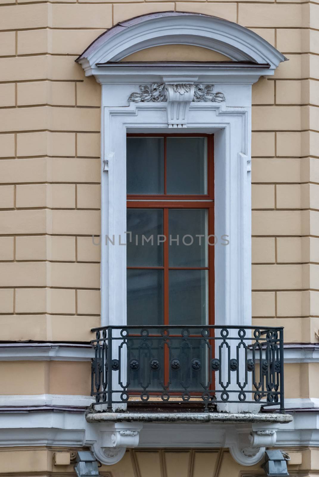 A window with an arch and balcony on the facade of the beige building. From the series window of Saint-Petersburg.