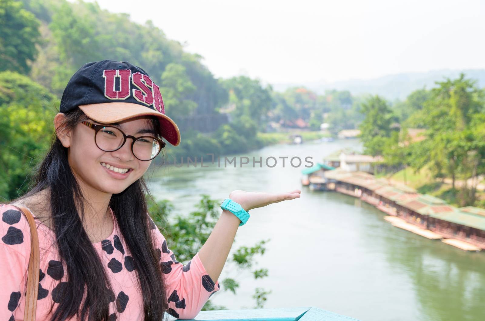 Tourist girl show hands invites to visit beautiful landscape of Death Railway bridge over the Kwai Noi River at Krasae cave viewpoint in Kanchanaburi province, Thailand