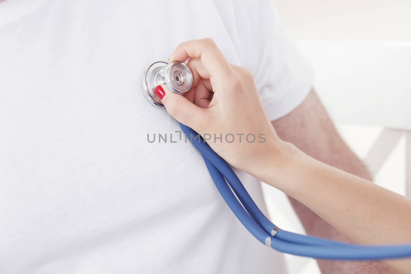 Doctor examining heartbeat with stethoscope, close-up view