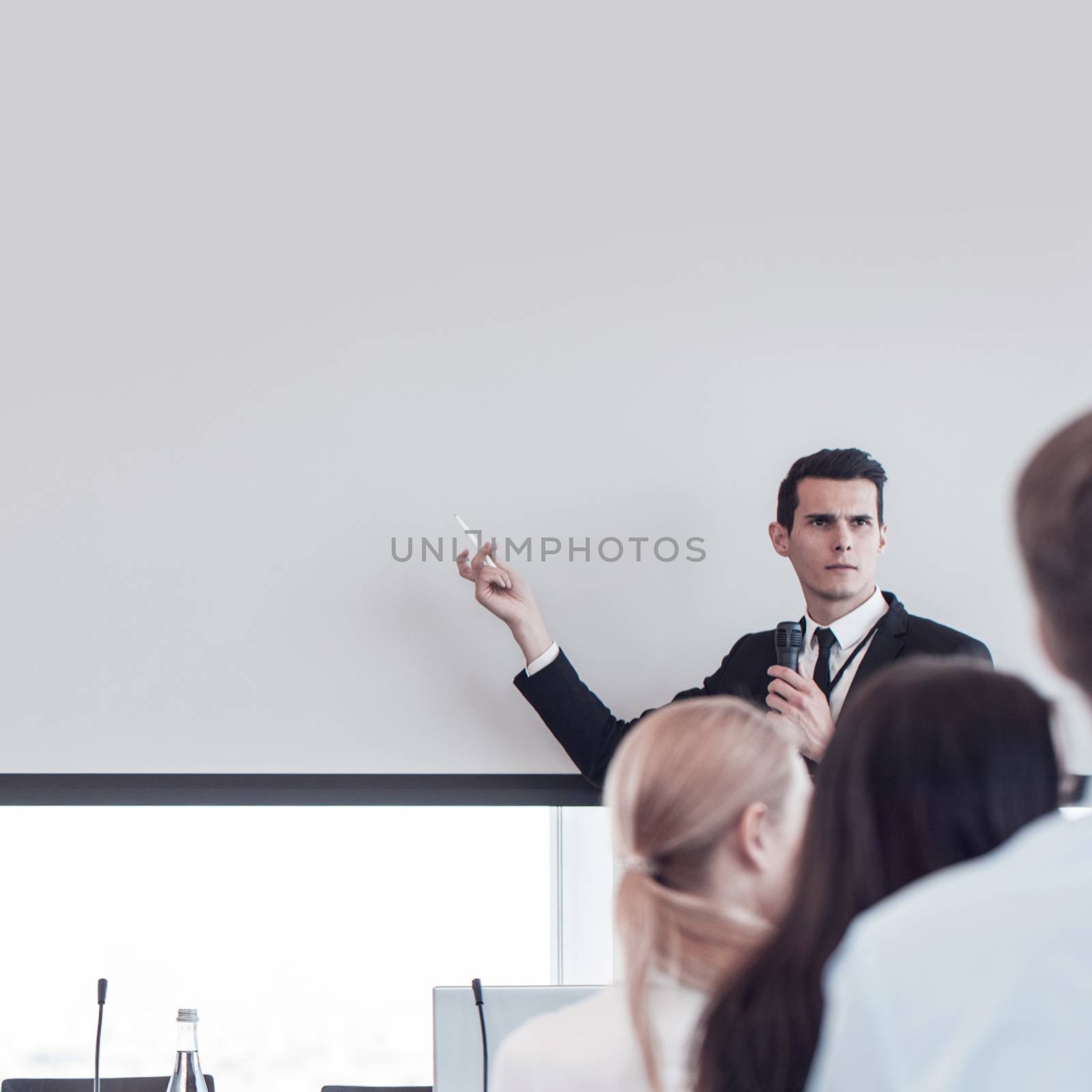 Business man speaking at presentation in microphone in office