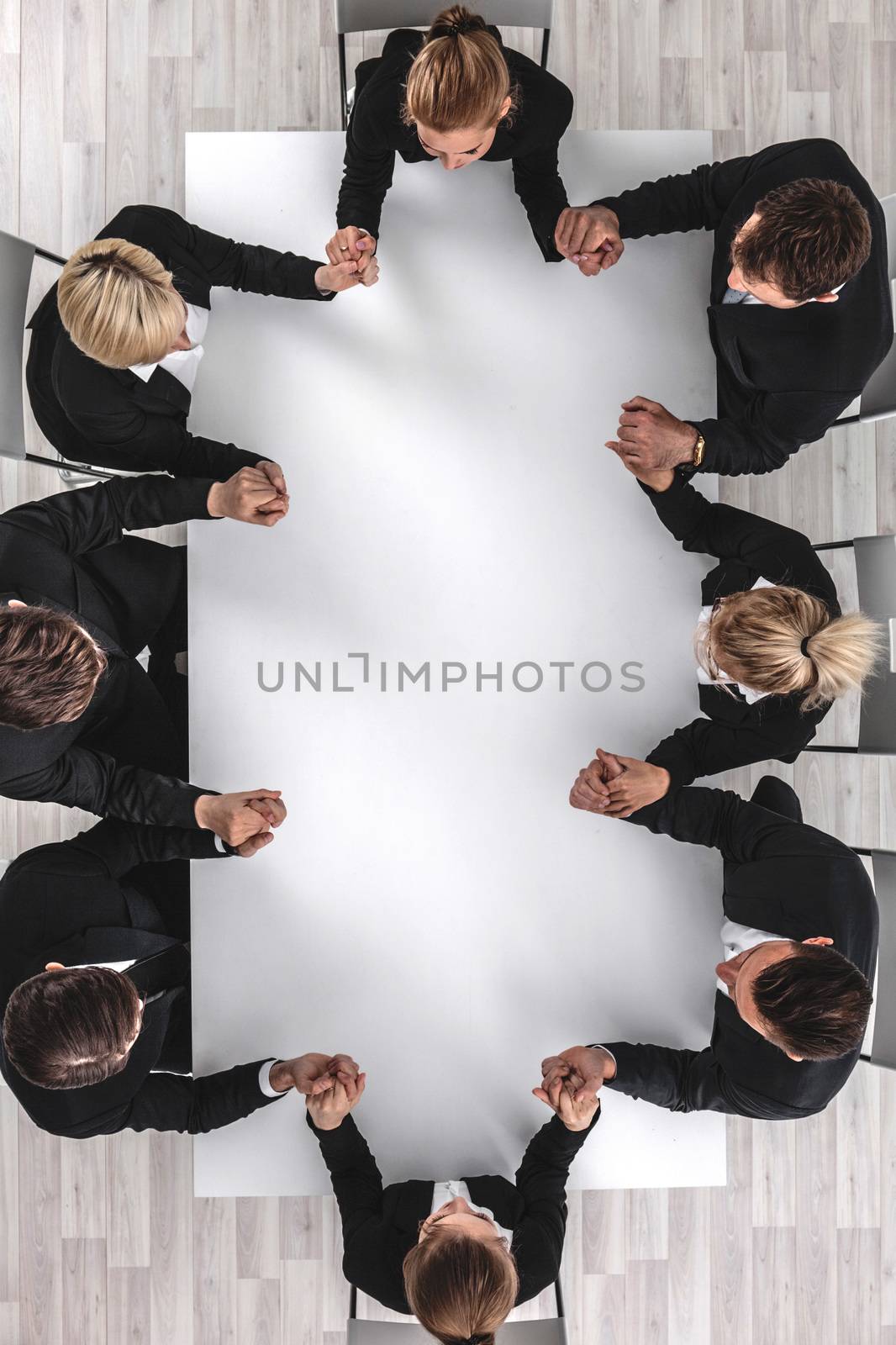 Diverse business people sitting around the table on a meeting and holding hands