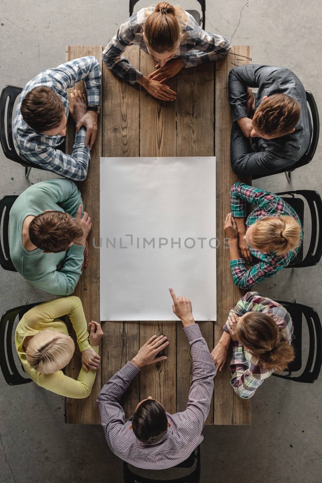 Hipster business teamwork brainstorming planning meeting concept, people sitting around the table with white paper