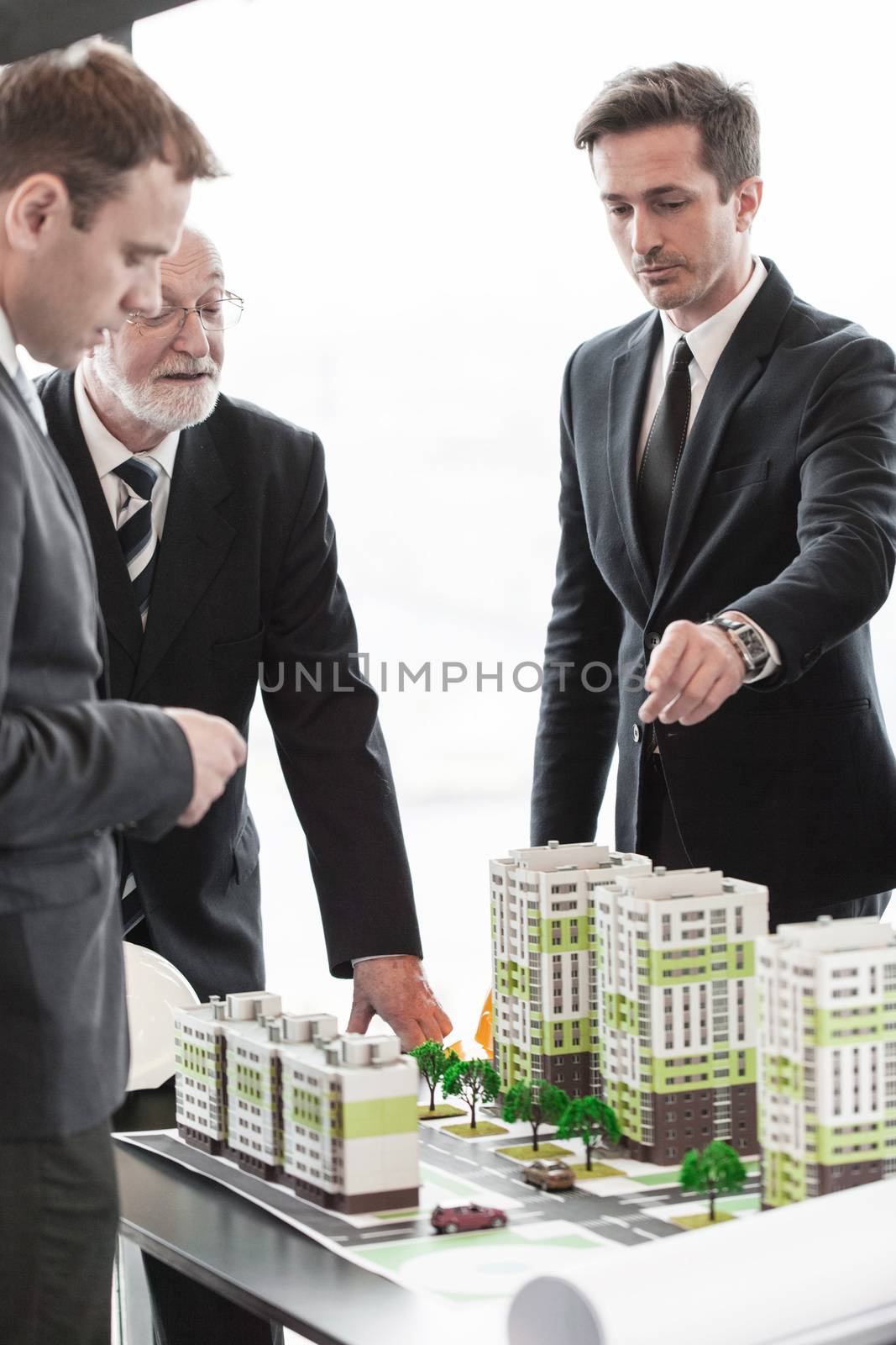 Business meeting of architects and investors looking at model of residential quarter houses