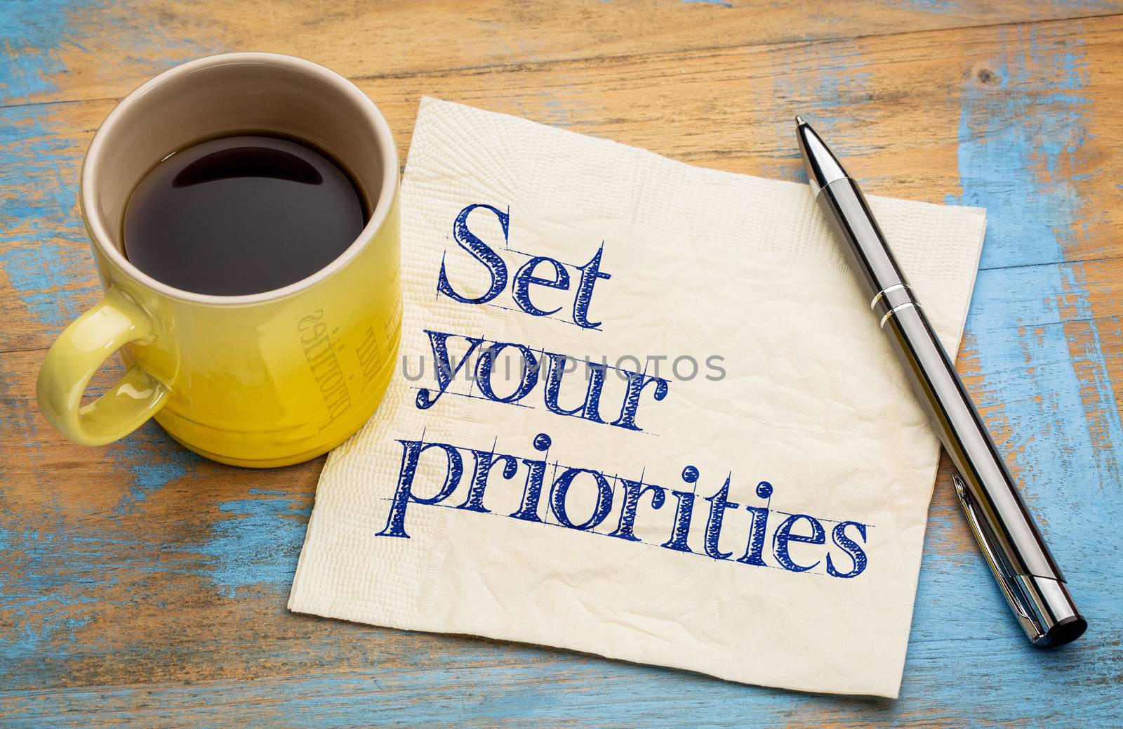 Set your priorities reminder - handwriting on a napkin with a cup of espresso coffee