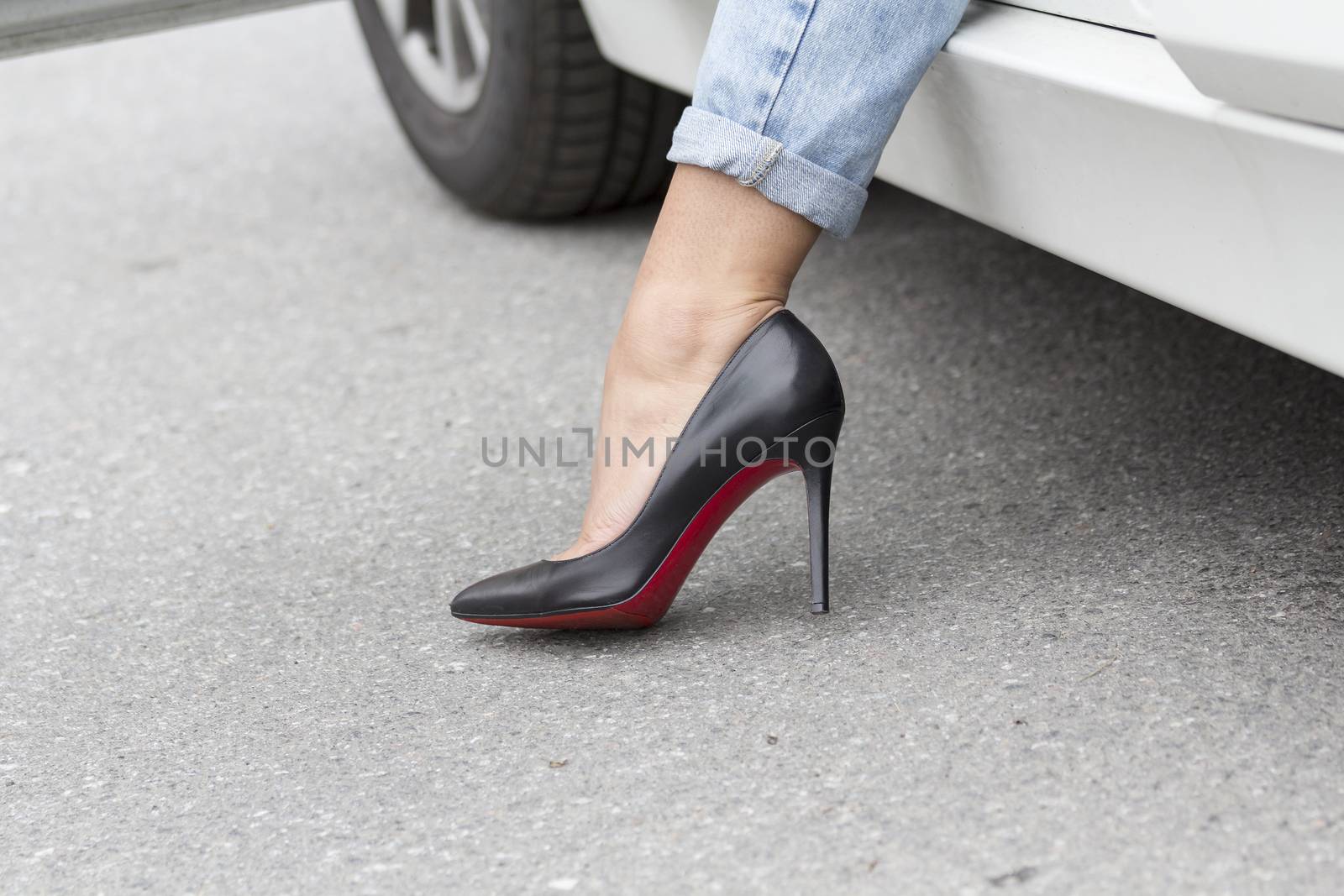 Feet girl in fashionable shoes near a car close-up on the road