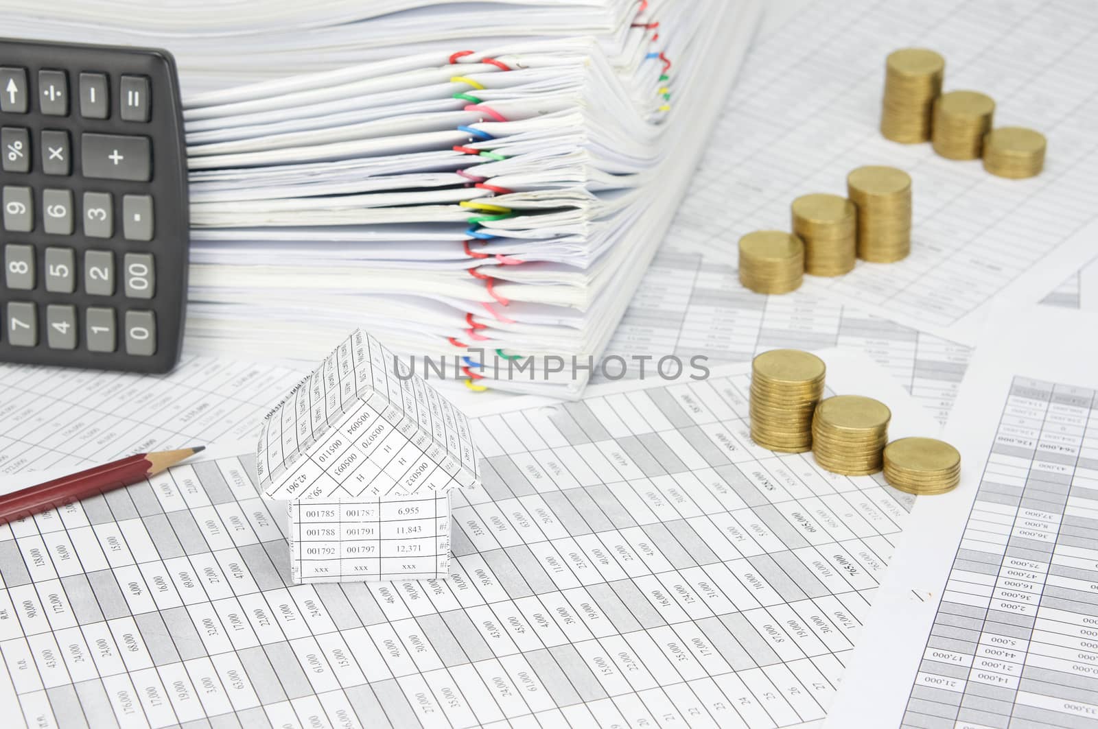 House on finance account have blur step pile of gold coins and pencil with calculator place vertical and pile paperwork of report with colorful paperclip as background.