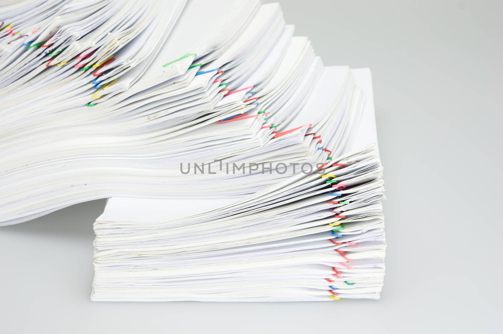 Pile overload paperwork of report and receipt with colorful paperclip place on white background.