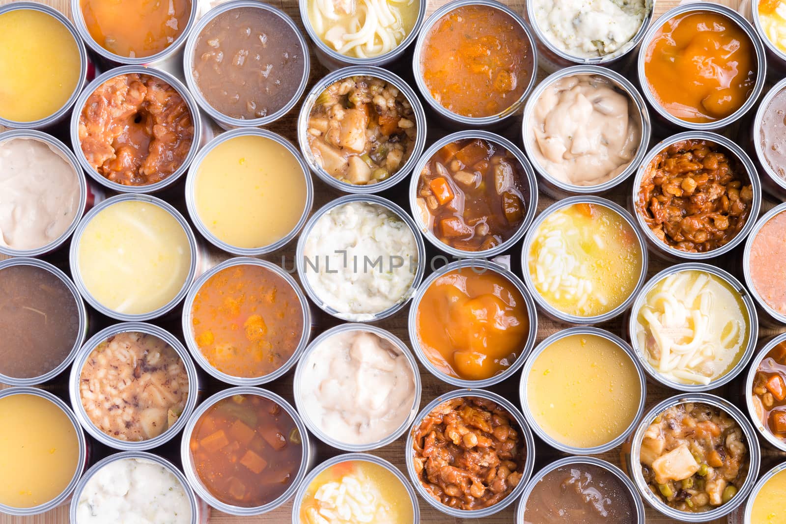 Colorful background of neatly arranged rows of opened cans of assorted soup viewed full frame from above in a food abstract still life