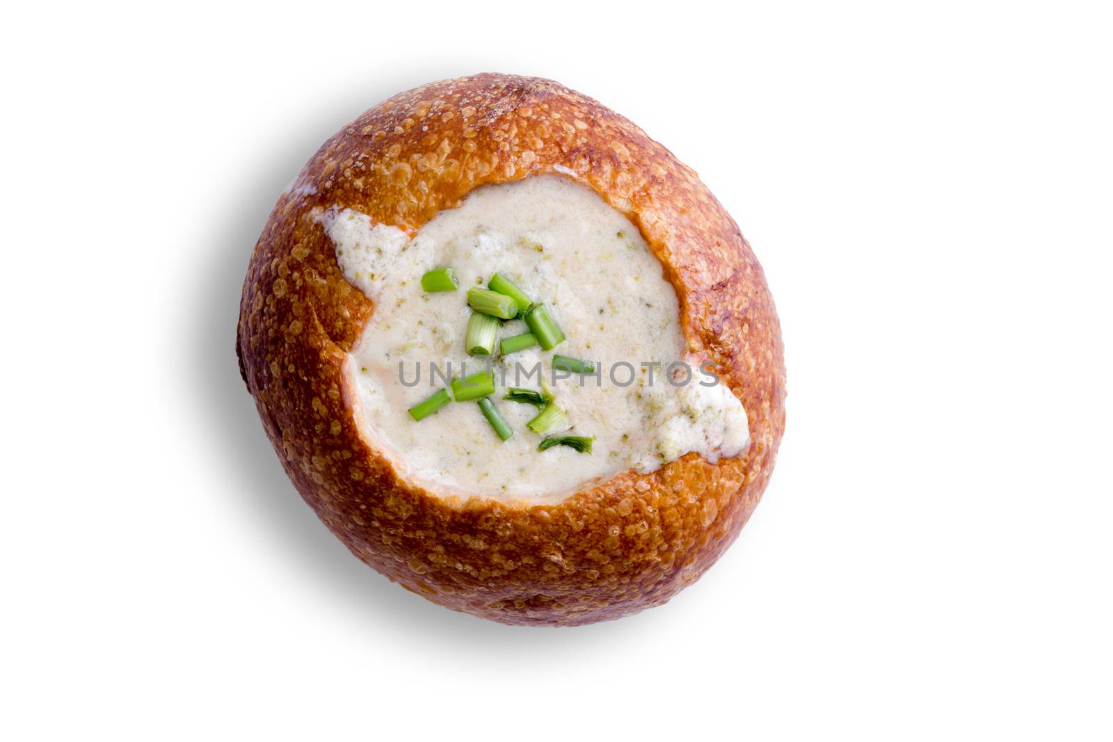 Delicious cream of broccoli soup in a bread bowl formed from a fresh crusty bun for a winter appetizer viewed overhead on white