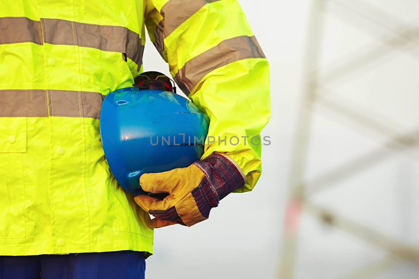 Arm of worker is holding protective helmet